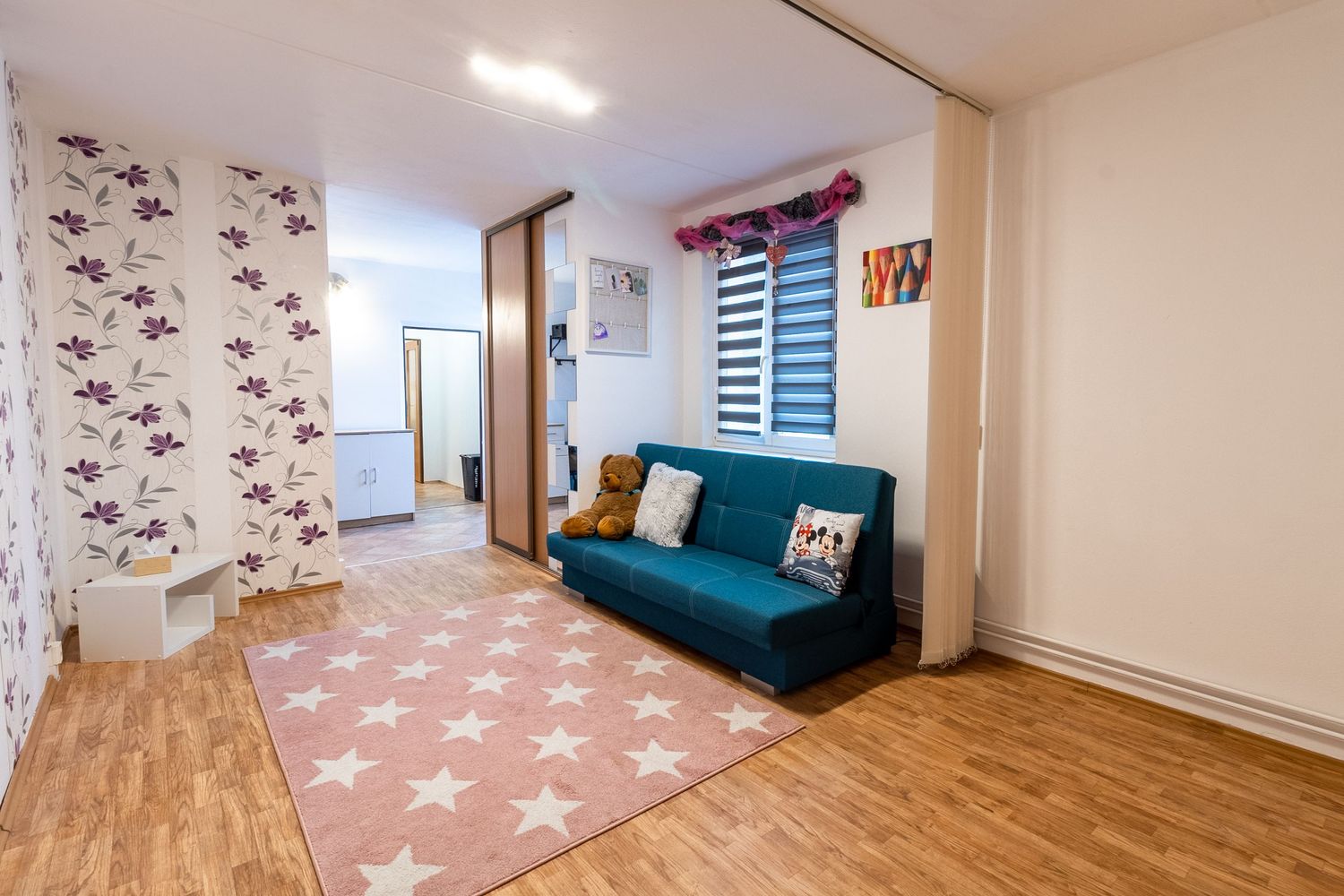 Living room with blue sofa, star pattern rug, and floral wallpaper accent wall.