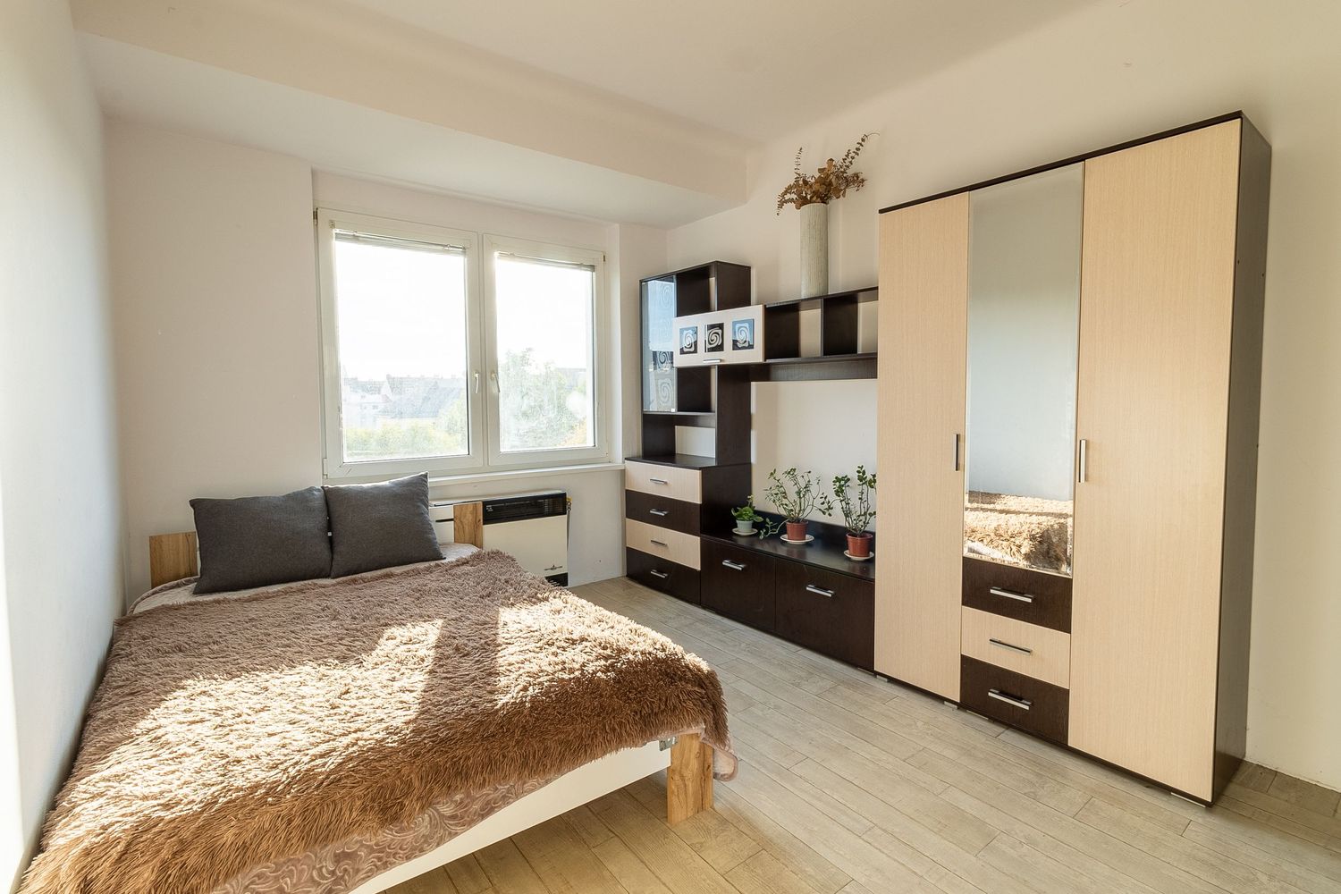 Contemporary bedroom with built-in wardrobe, wooden bed and light laminate flooring.