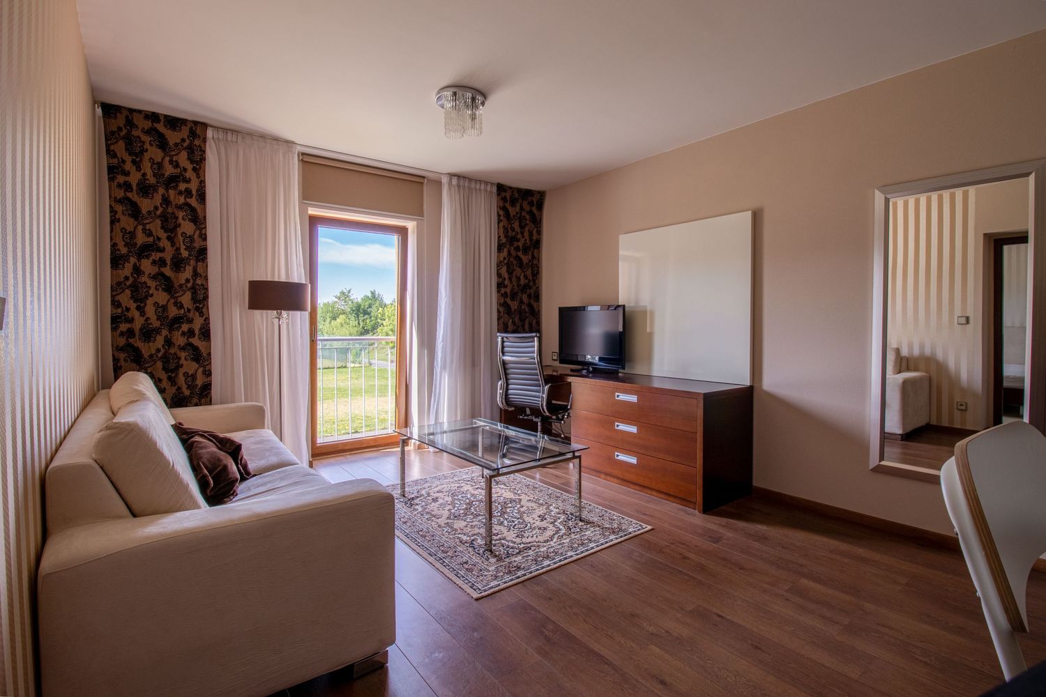 Modern living room interior with beige walls, wooden floor and large window with natural light.
