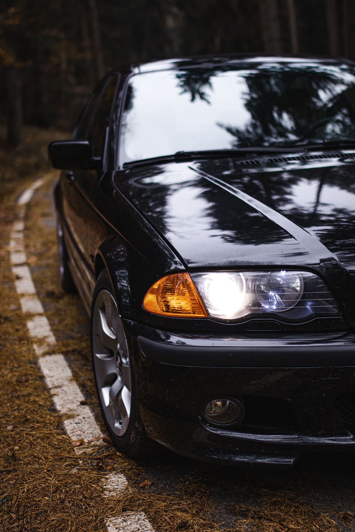Close-up shot of black BMW headlight with amber turn signal illuminated.