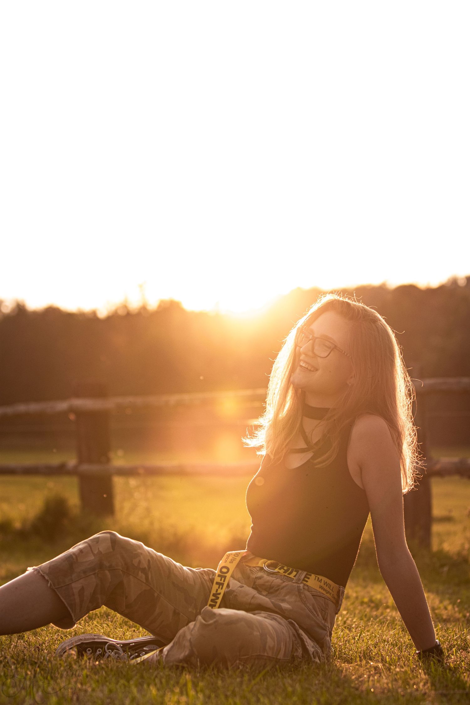 Person relaxing in golden sunlight on grassy field during sunset.