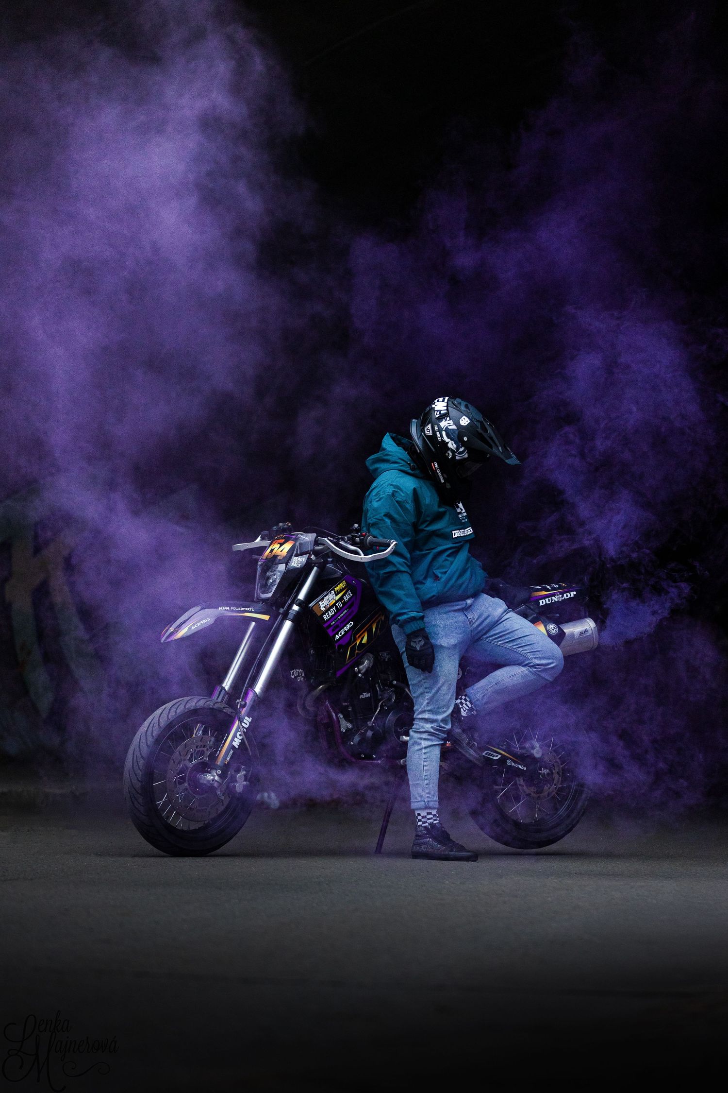 Motorcycle rider in purple smoke creates dramatic atmospheric effect.