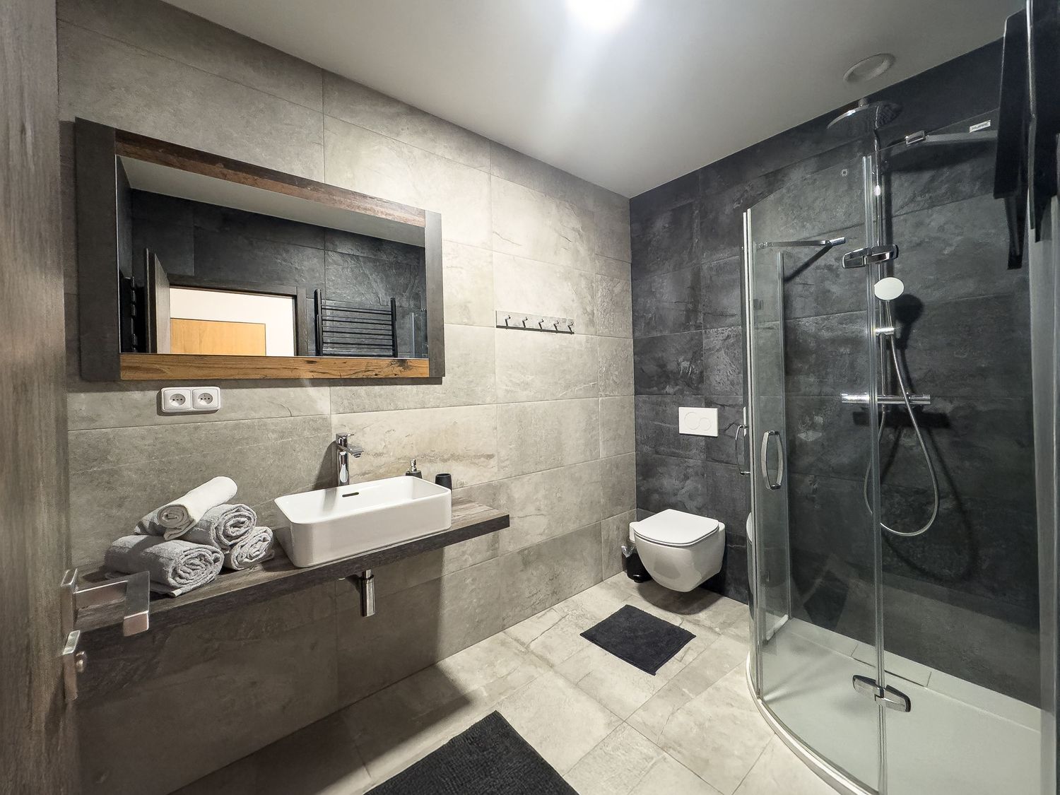 Modern bathroom design with concrete walls, glass shower enclosure, and sleek fixtures in a minimalist style.