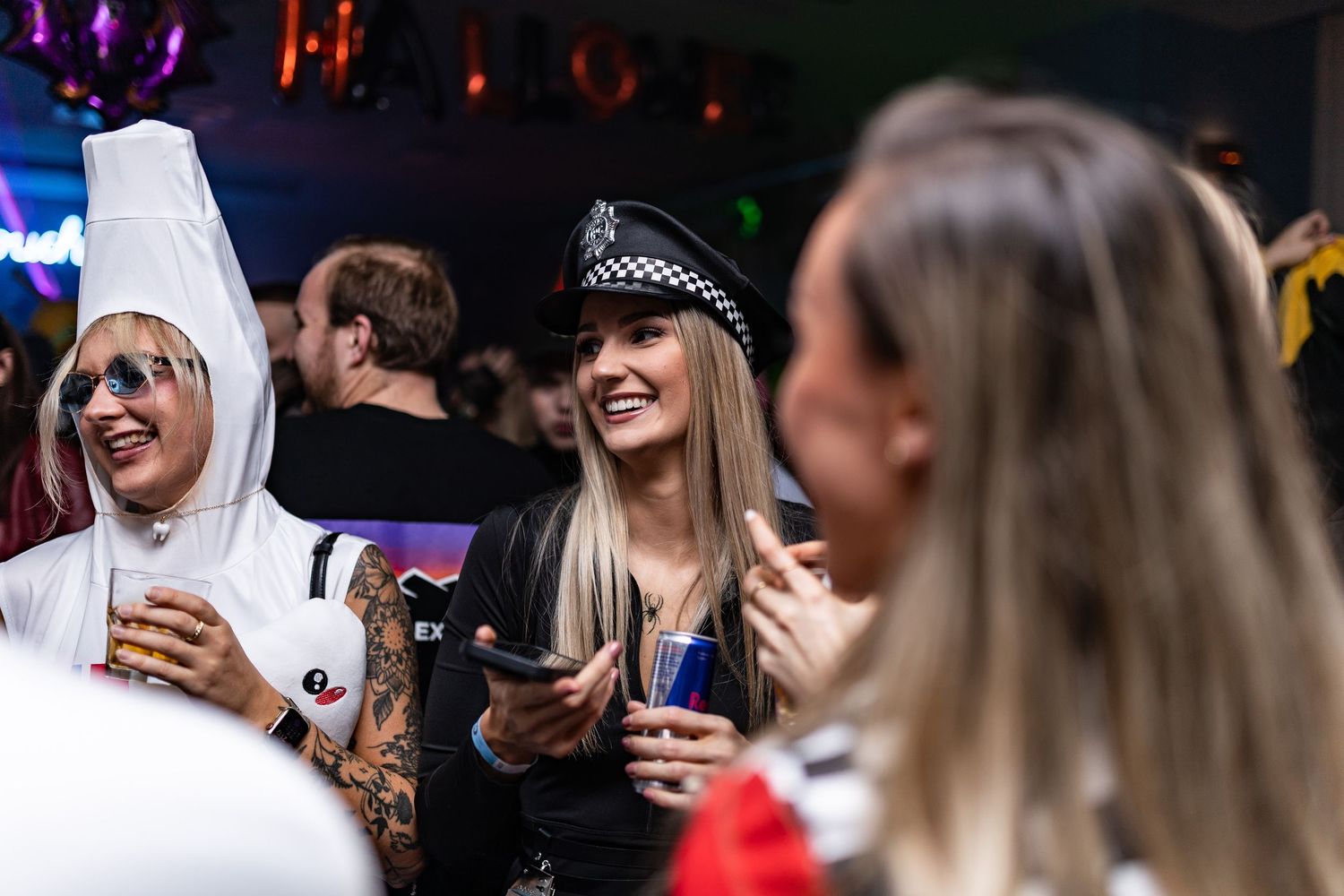 Crowd of people enjoying themselves at a nightclub with colorful lighting and festive atmosphere.