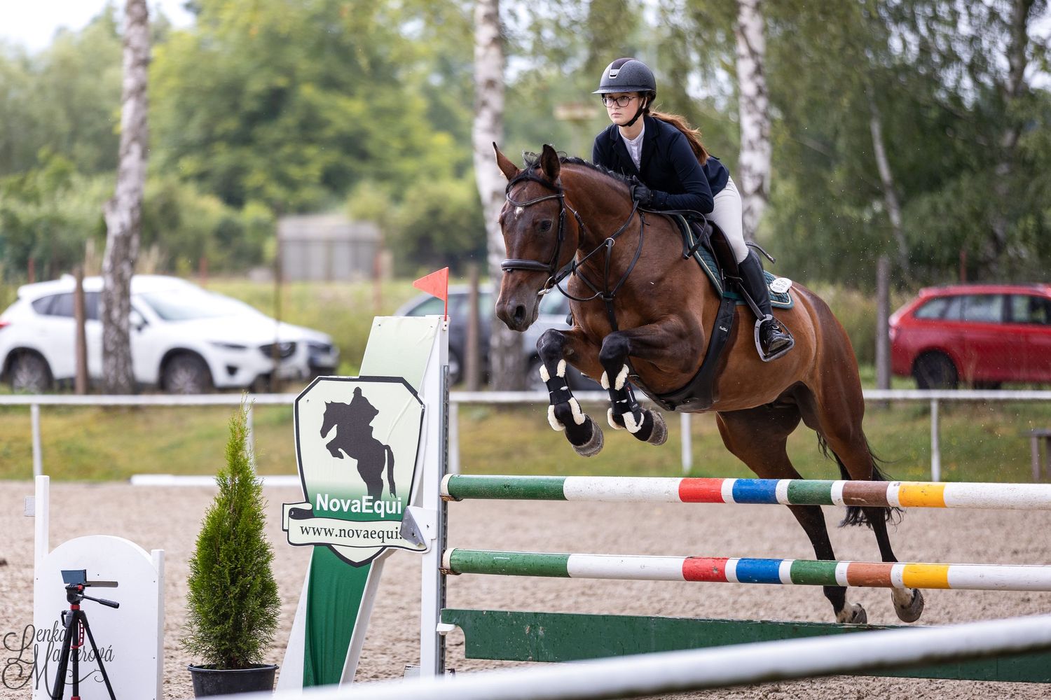 Horse and rider clear a jump during an equestrian show jumping competition at an outdoor arena.