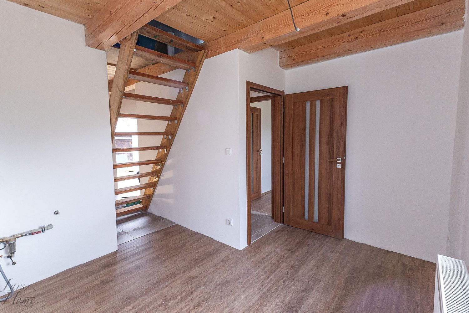 Modern loft apartment interior with wooden beams and hardwood flooring showcases an open concept design.
