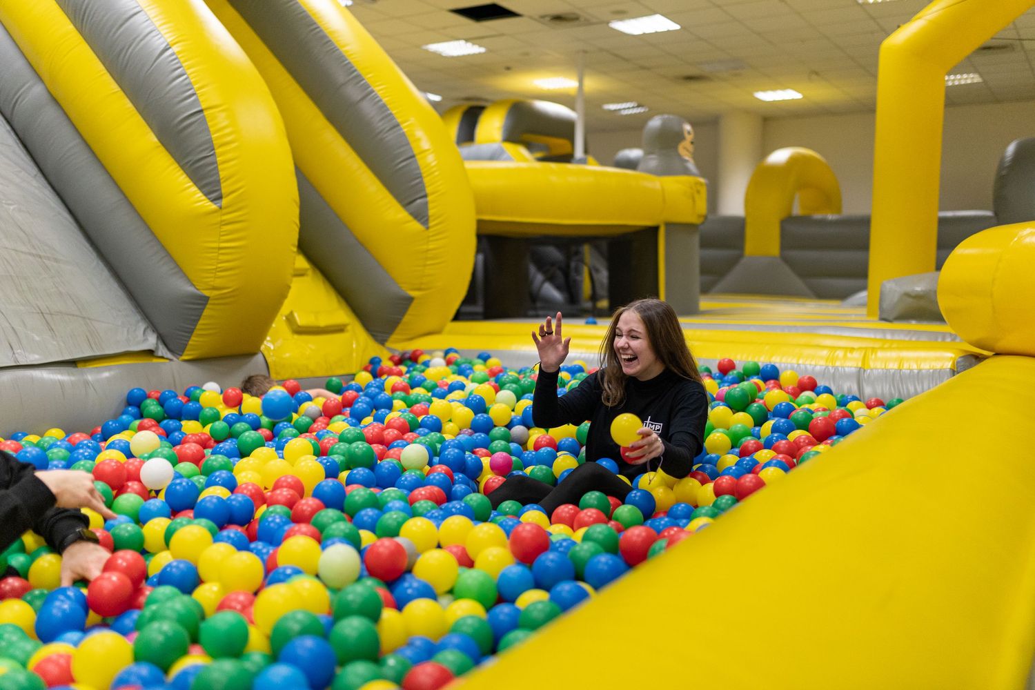 Colorful ball pit with bright yellow inflatable obstacles creates an indoor playground atmosphere.