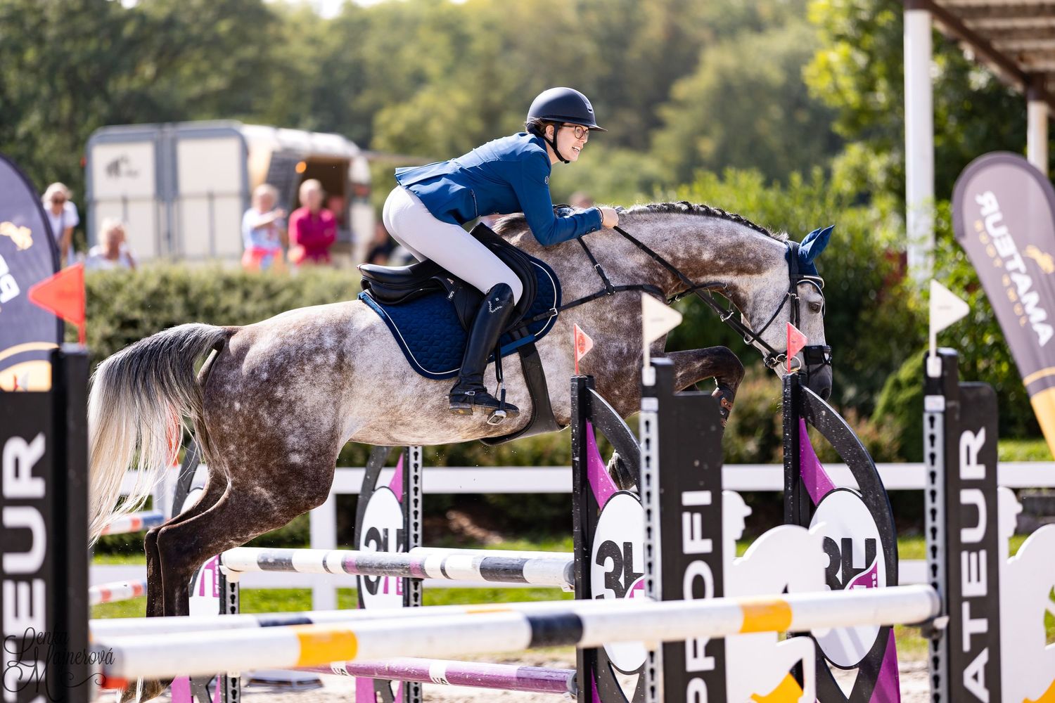 A horse and rider navigate through a series of colorful show jumping obstacles during an equestrian competition.