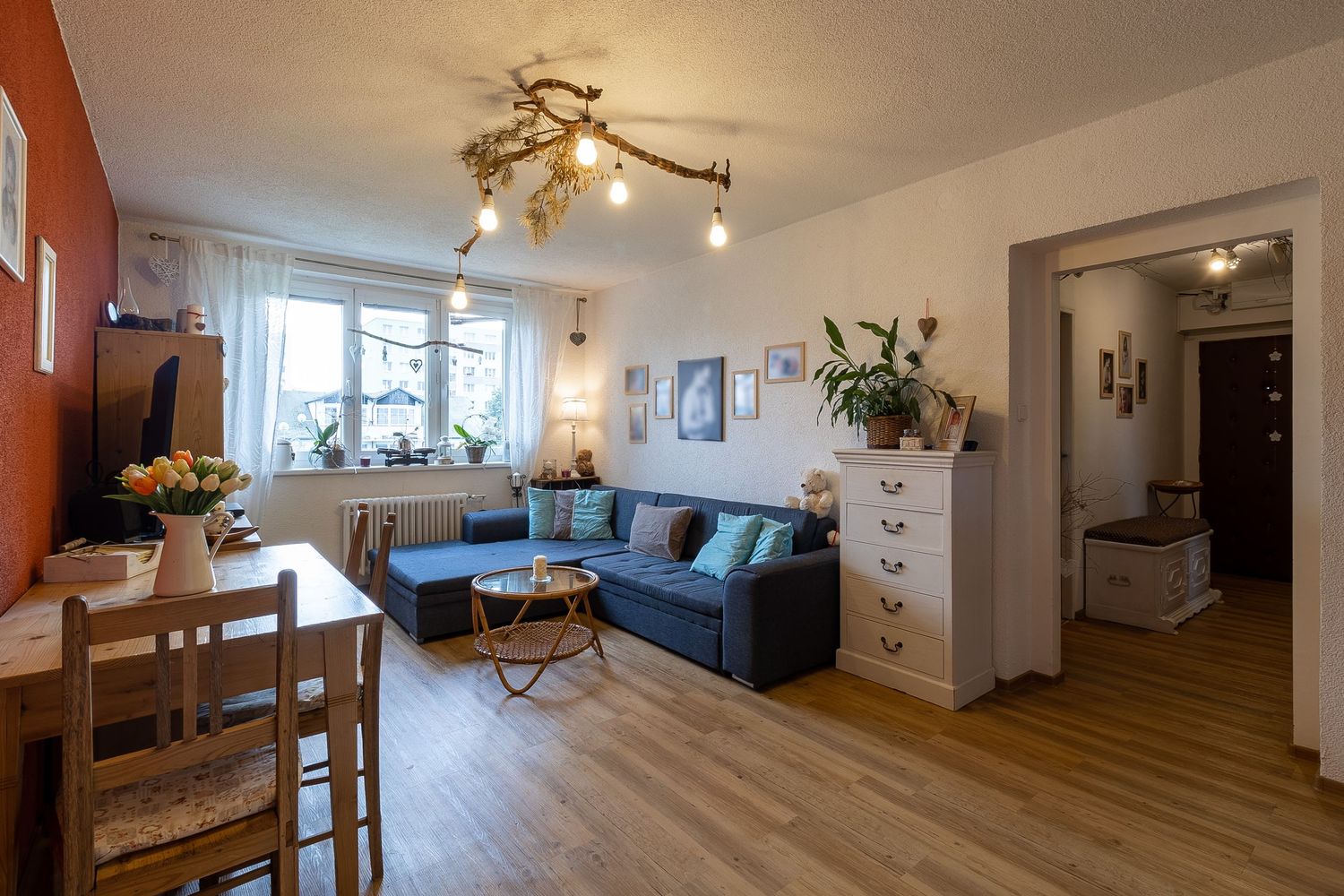 Cozy living room with blue sofa, dining area, and orange accent wall in modern apartment.