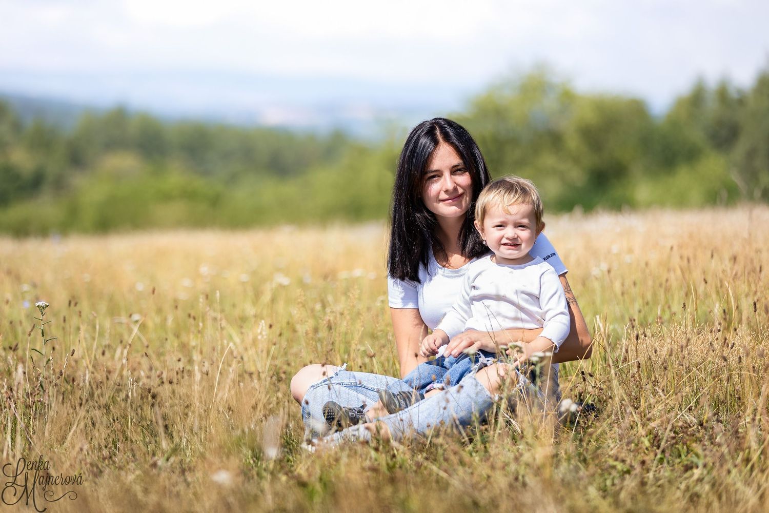 Mother and baby laying in a golden wheat field on a sunny summer day.