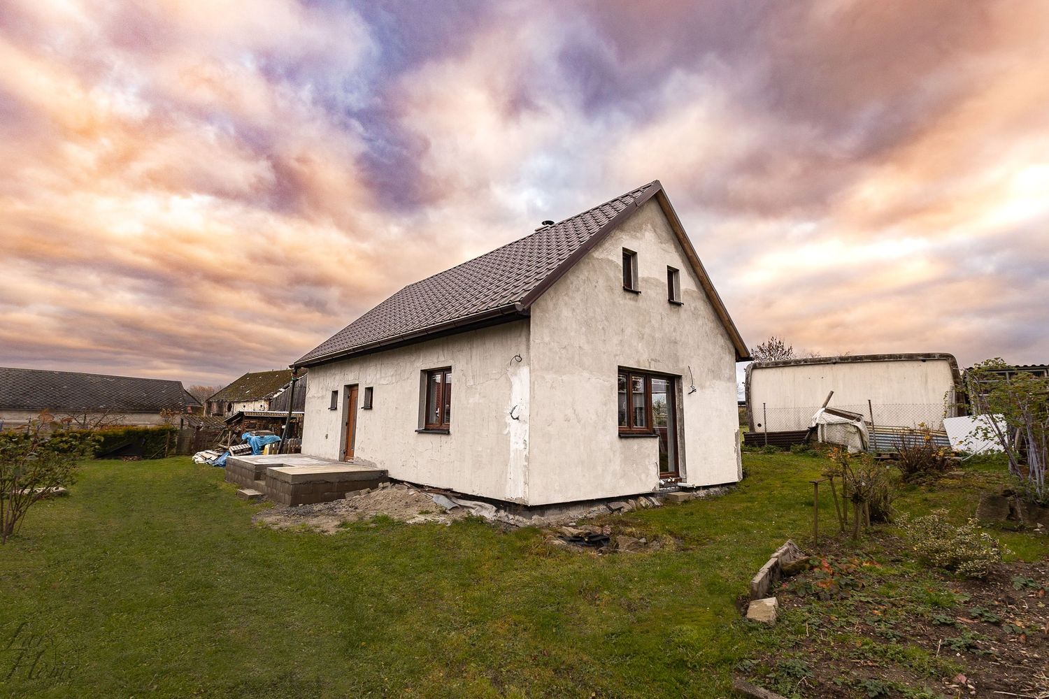 A panoramic view of traditional white-washed rural cottages against a dramatic sunset sky in the Scottish countryside.