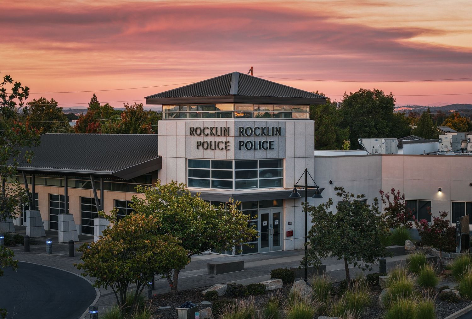 Panoramic view of police station exterior with pink and purple sunset sky.