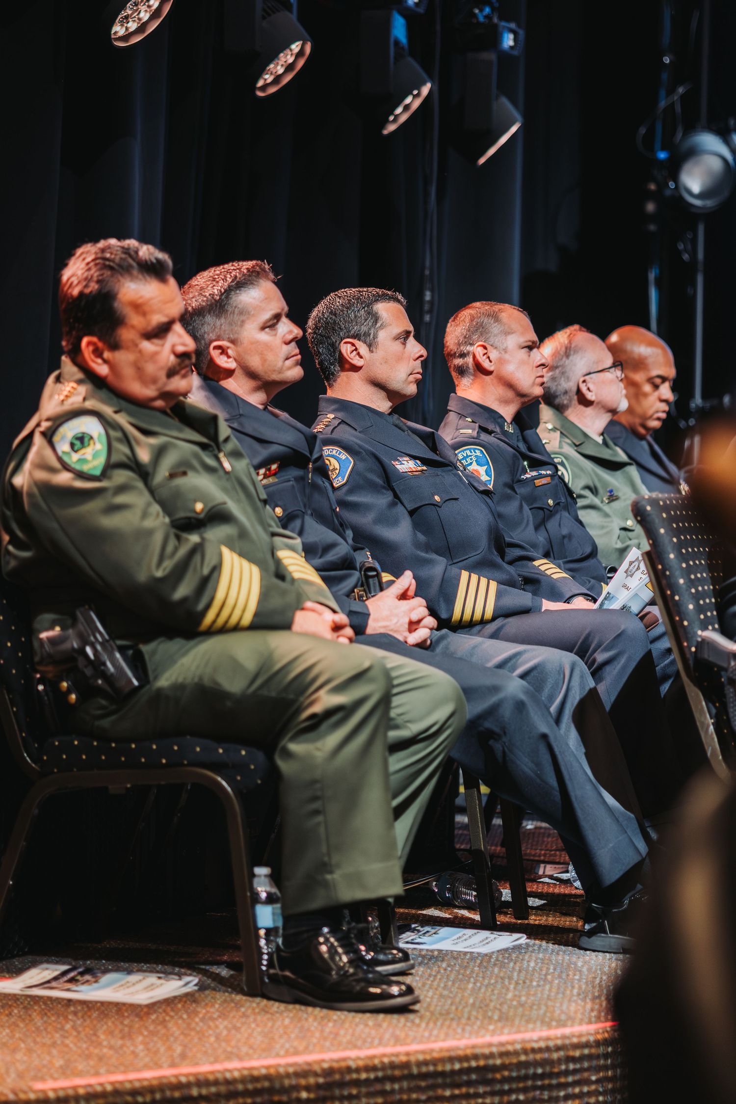 Military and law enforcement personnel seated in a dark auditorium during a presentation.