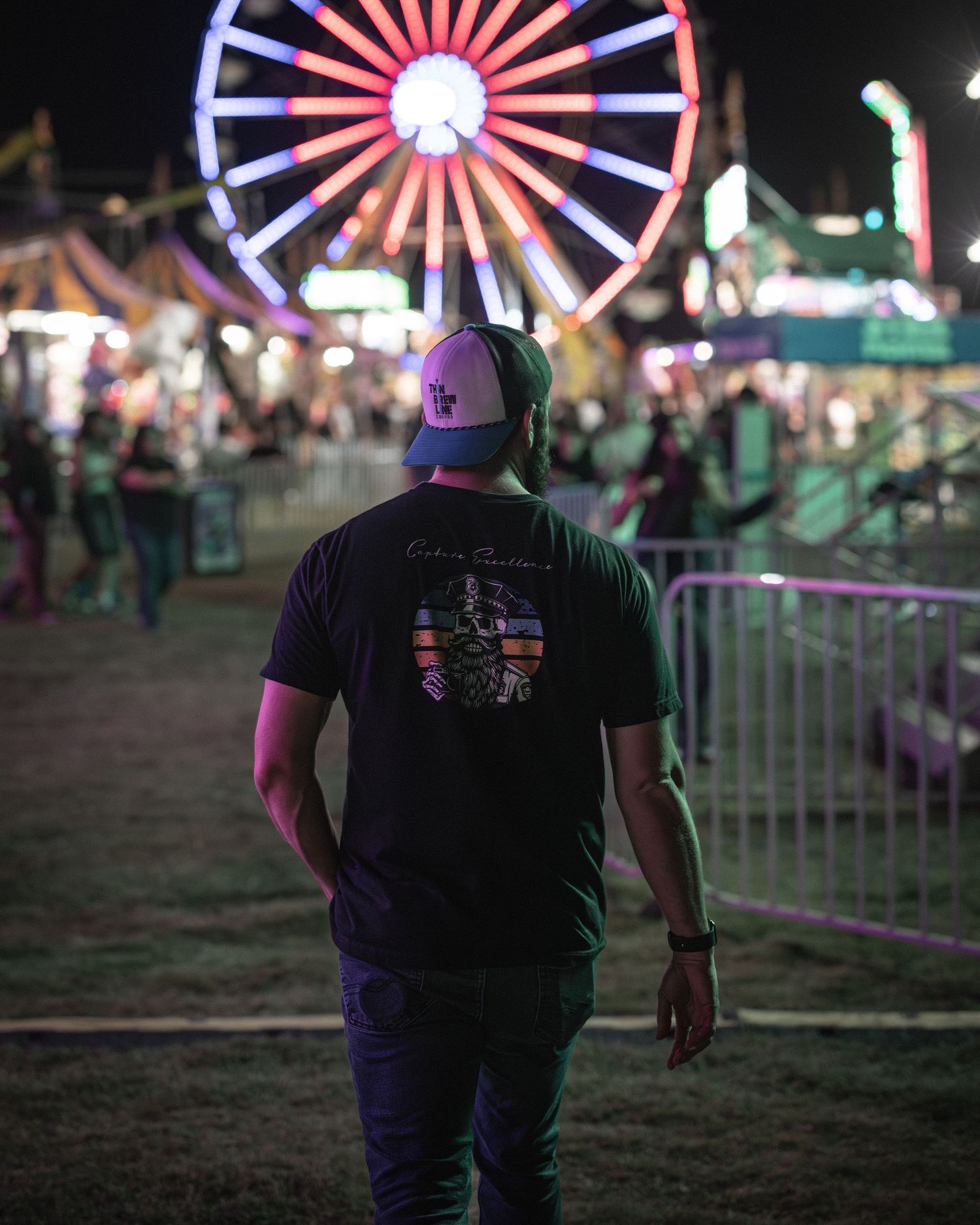 Illuminated ferris wheel glowing with red and white lights against dark night sky at carnival.