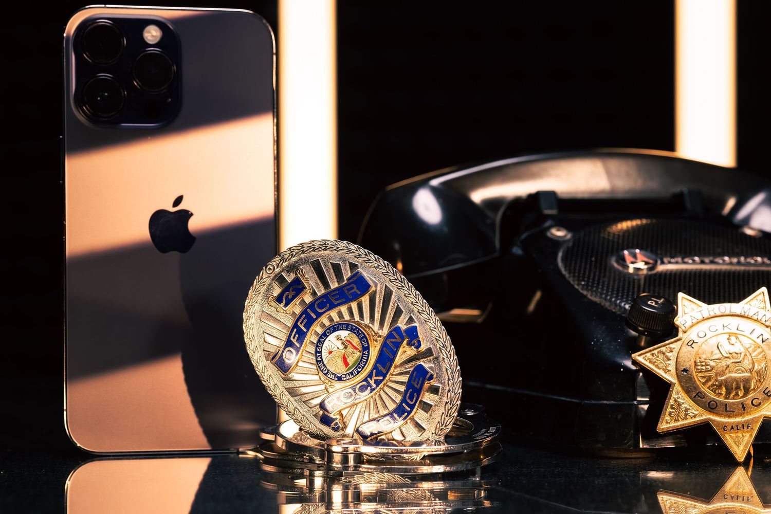 Police badges and law enforcement emblems photographed in dramatic low-key lighting.