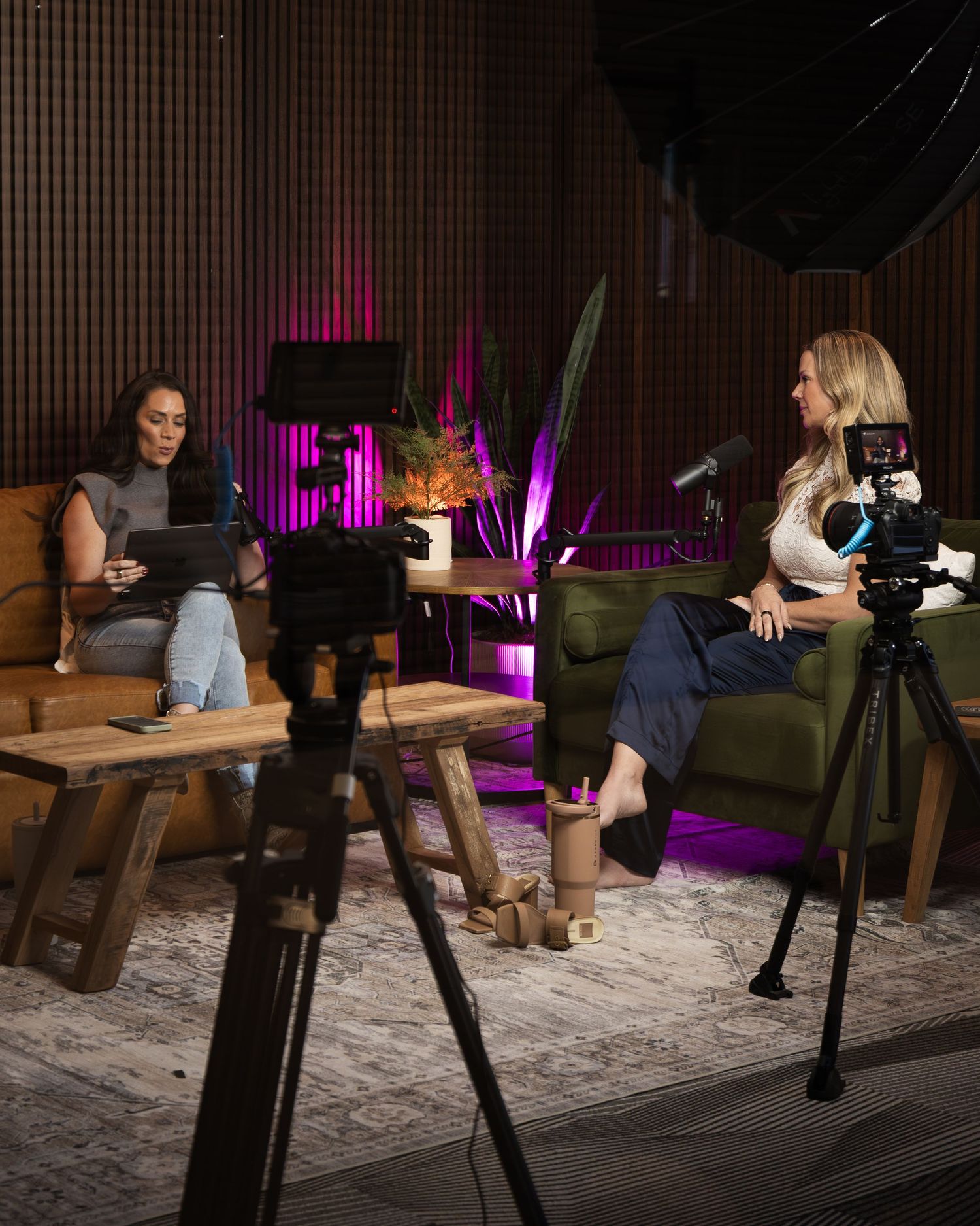A photographer captures content at a wooden table in a dimly lit room with purple accent lighting.