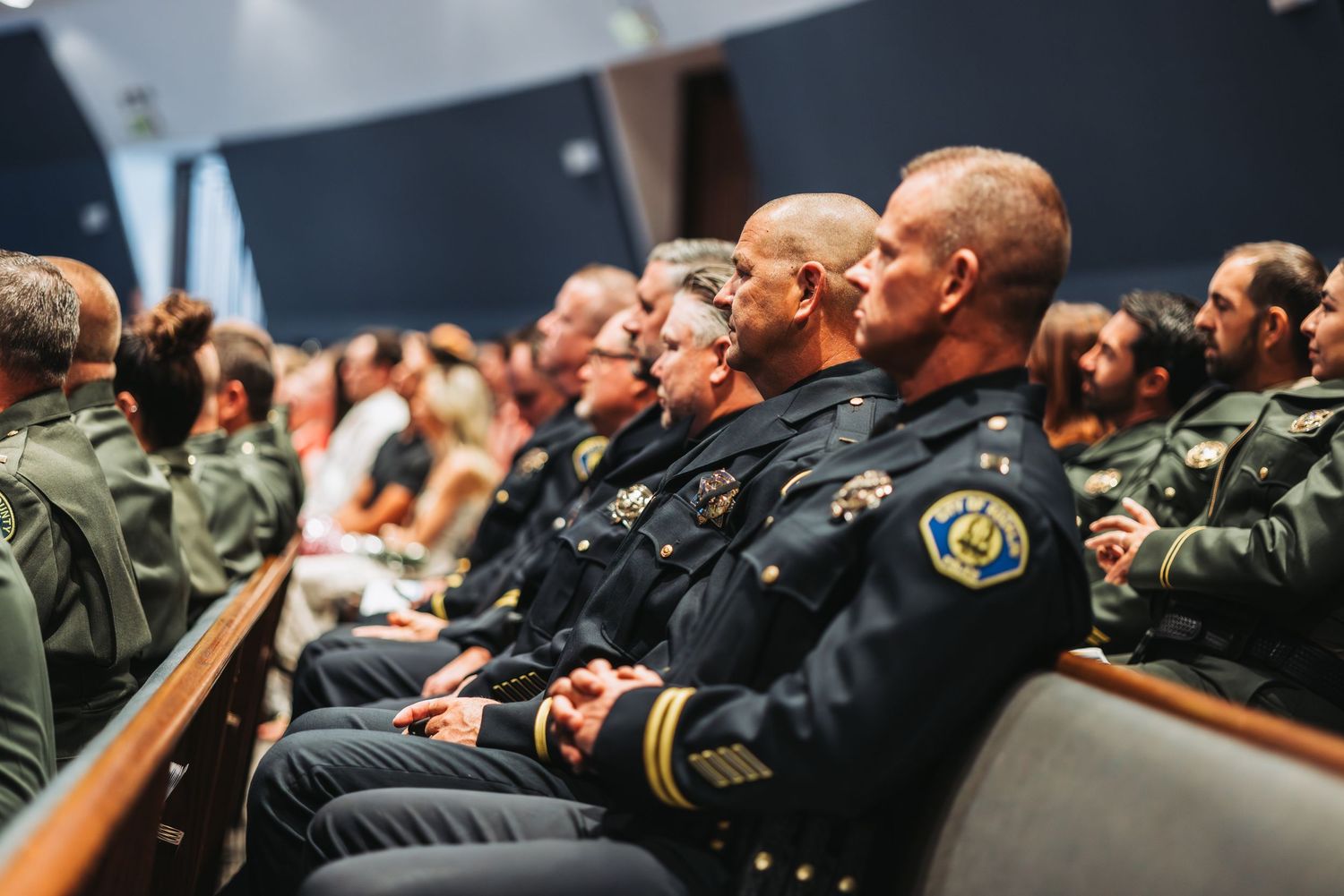 Law enforcement officers seated in rows during a formal training or briefing session.