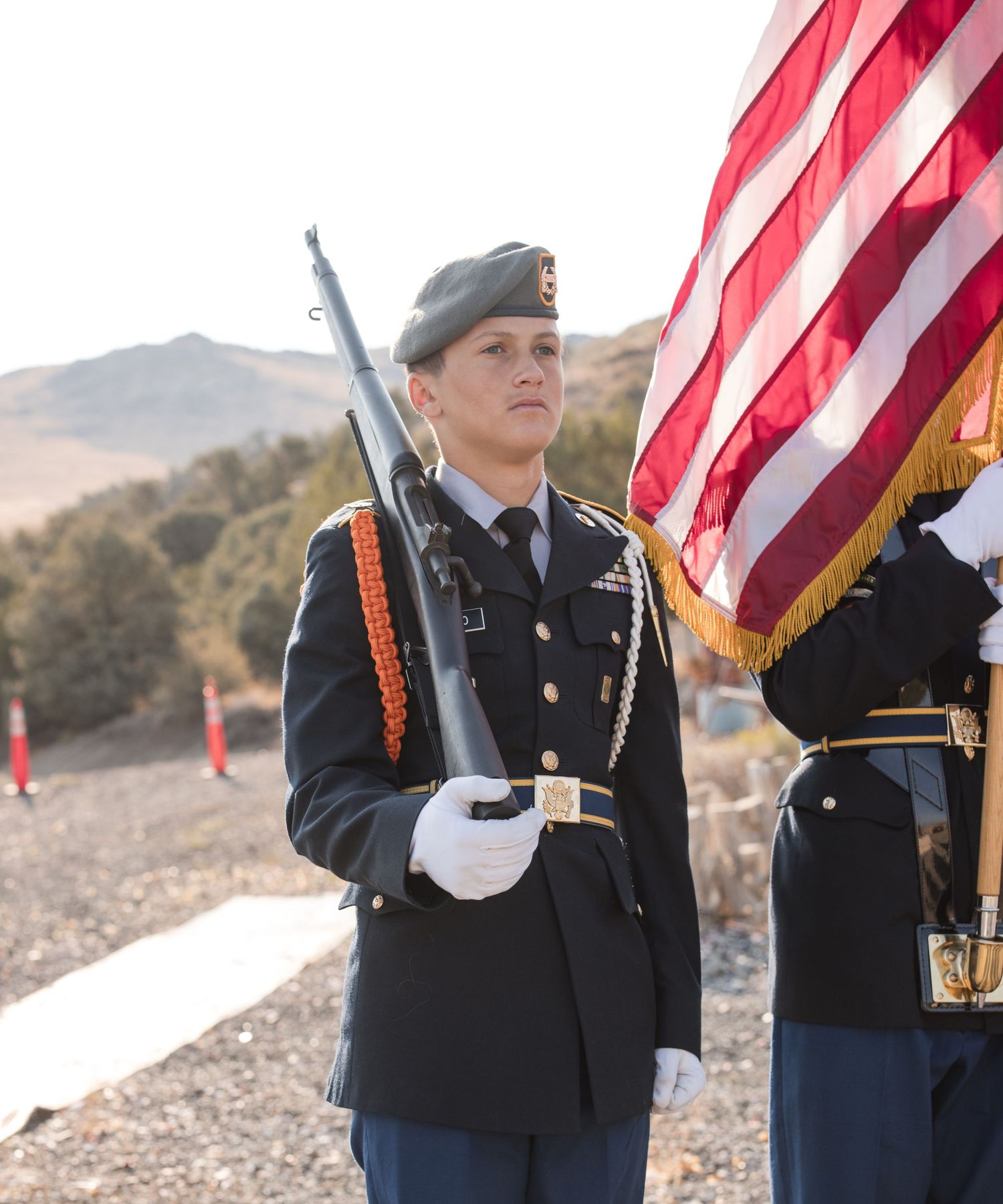 Military honor guard members perform a ceremonial flag presentation during an outdoor event.