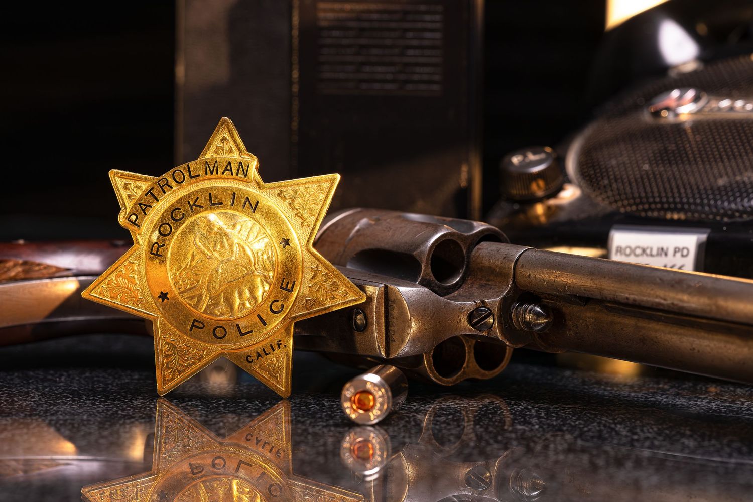 A collection of vintage sheriff badges and law enforcement equipment arranged on a dark surface.