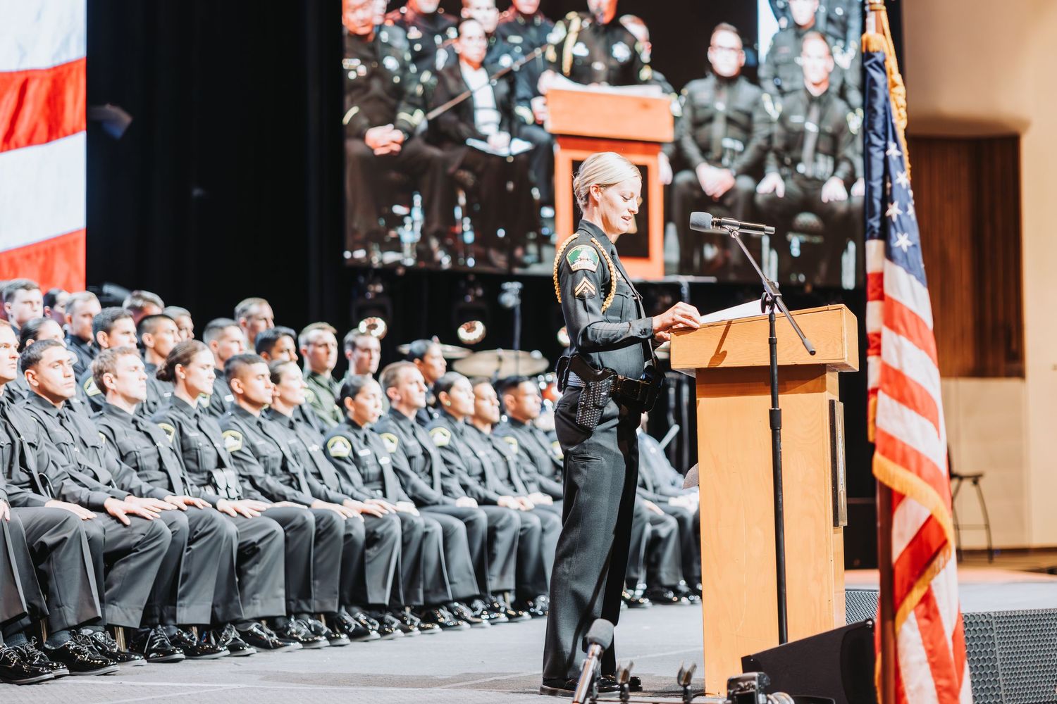 Police officers standing in formation at an official ceremony with American flags visible.