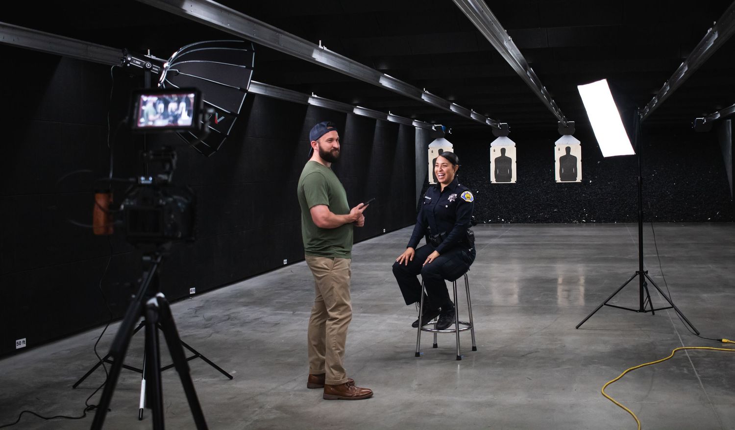 Behind the scenes photo shoot setup in a dark studio with lighting equipment and crew members working.