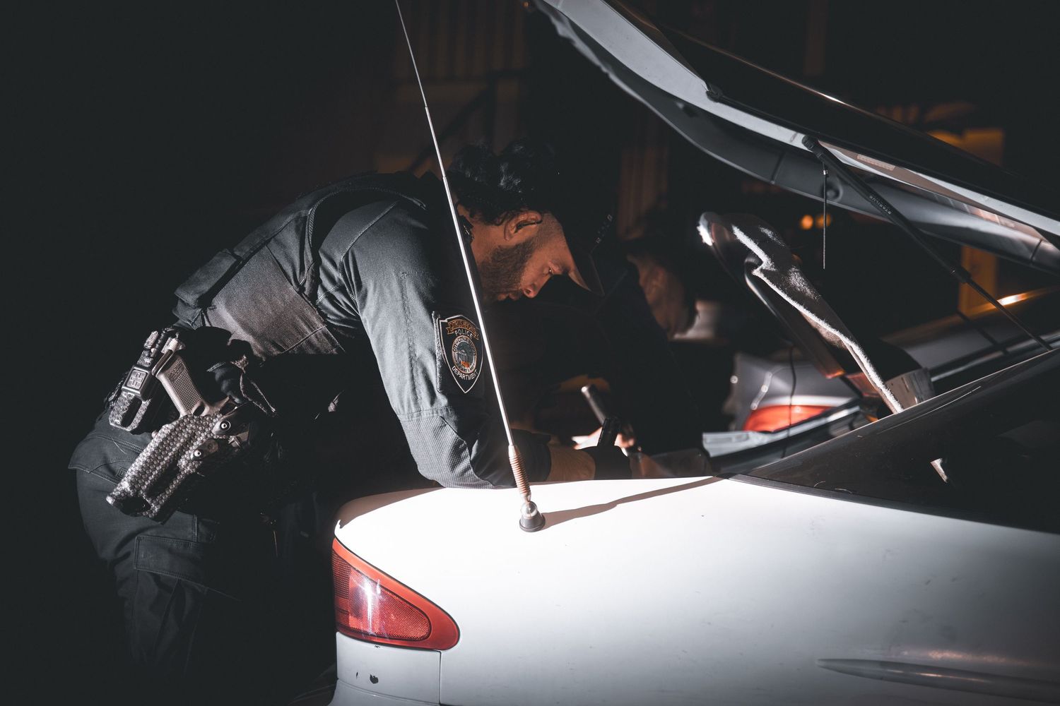 A sleek silver sports car is shown in dramatic low lighting against a dark background.
