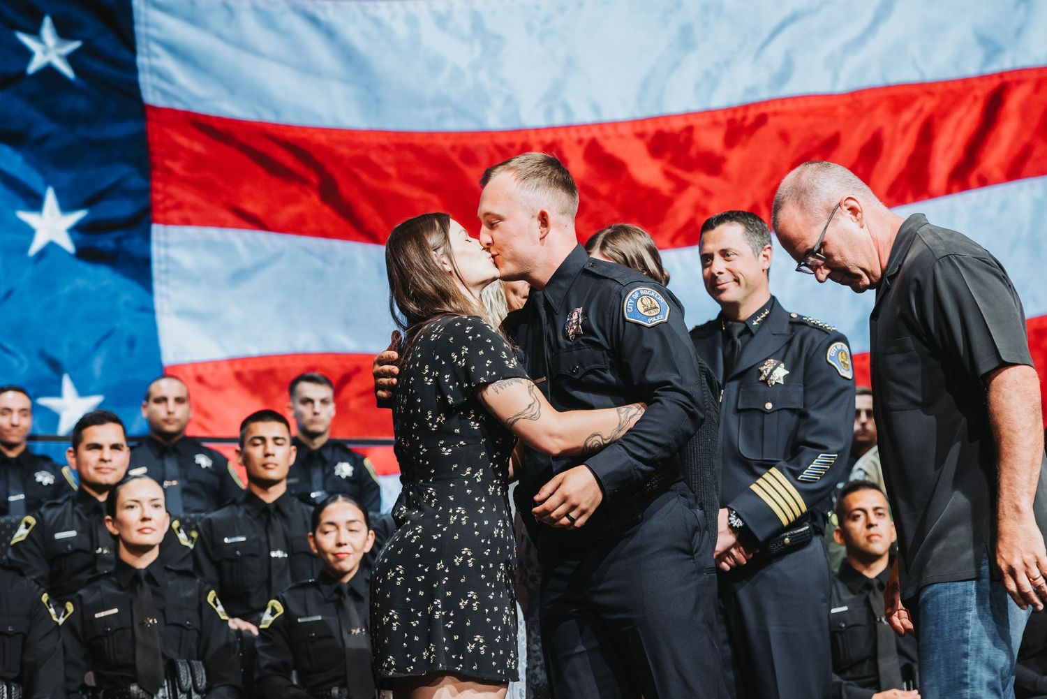 Group of police officers gathered in front of an American flag during a ceremony.