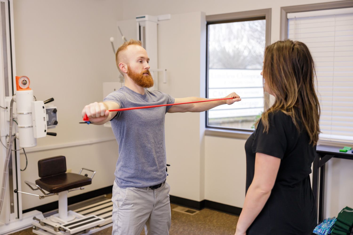 man demonstrating resistance bands to woman patient in chiropractic office for after care health and knowledge in Tacoma, WA