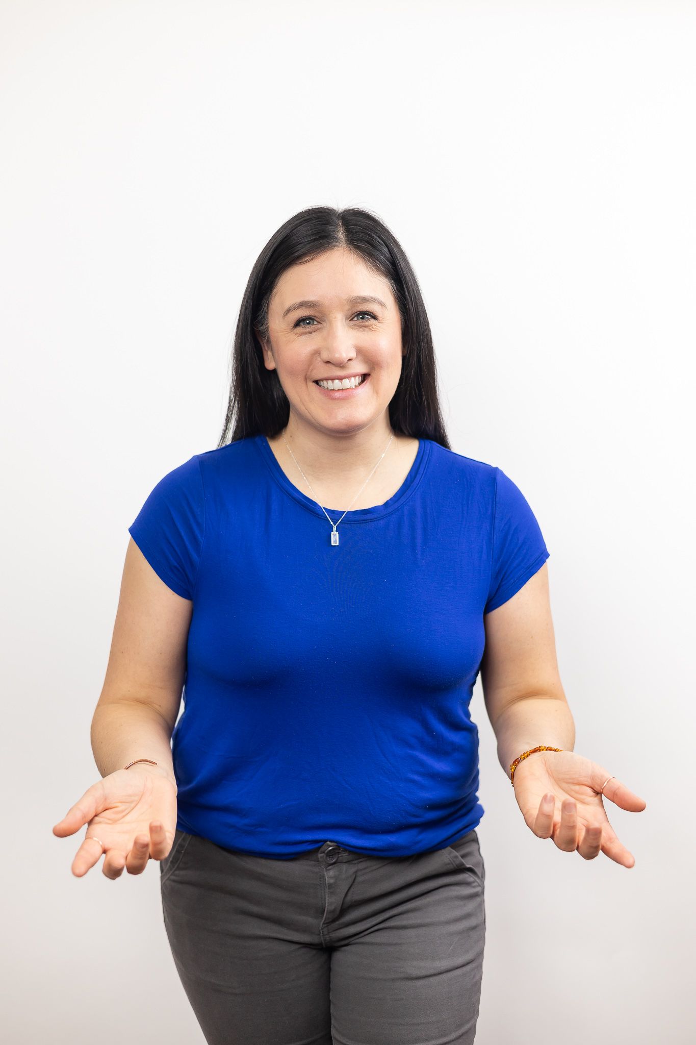 woman standing with palms up showing empty hands smiling and wearing a blue shirt on white background for lifestyle education photo Seattle