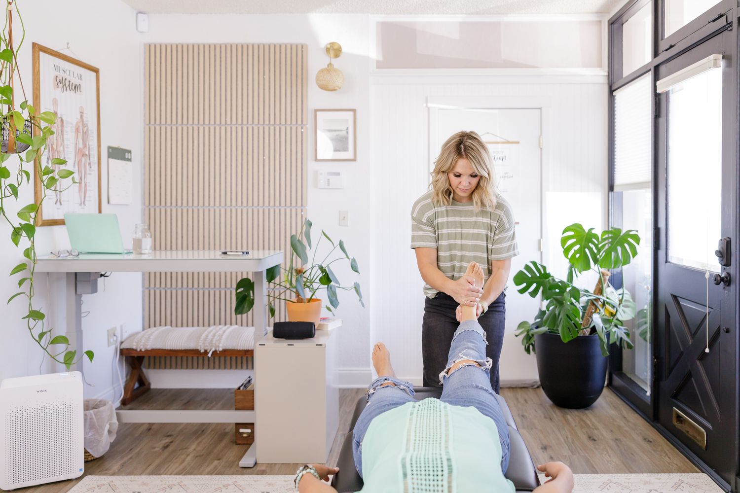 female chiropractor check leg length while laying face up for client model in office space branding photo in Tacoma, WA