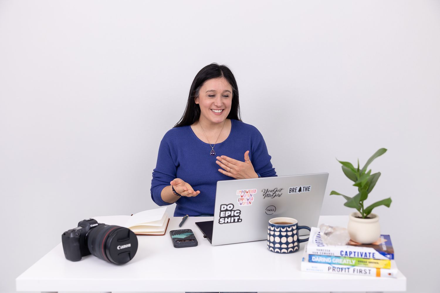 woman photographer sitting at desk on video call talking to client in Auburn, WA studio for lifestyle brand photo. Camera, notebook, books