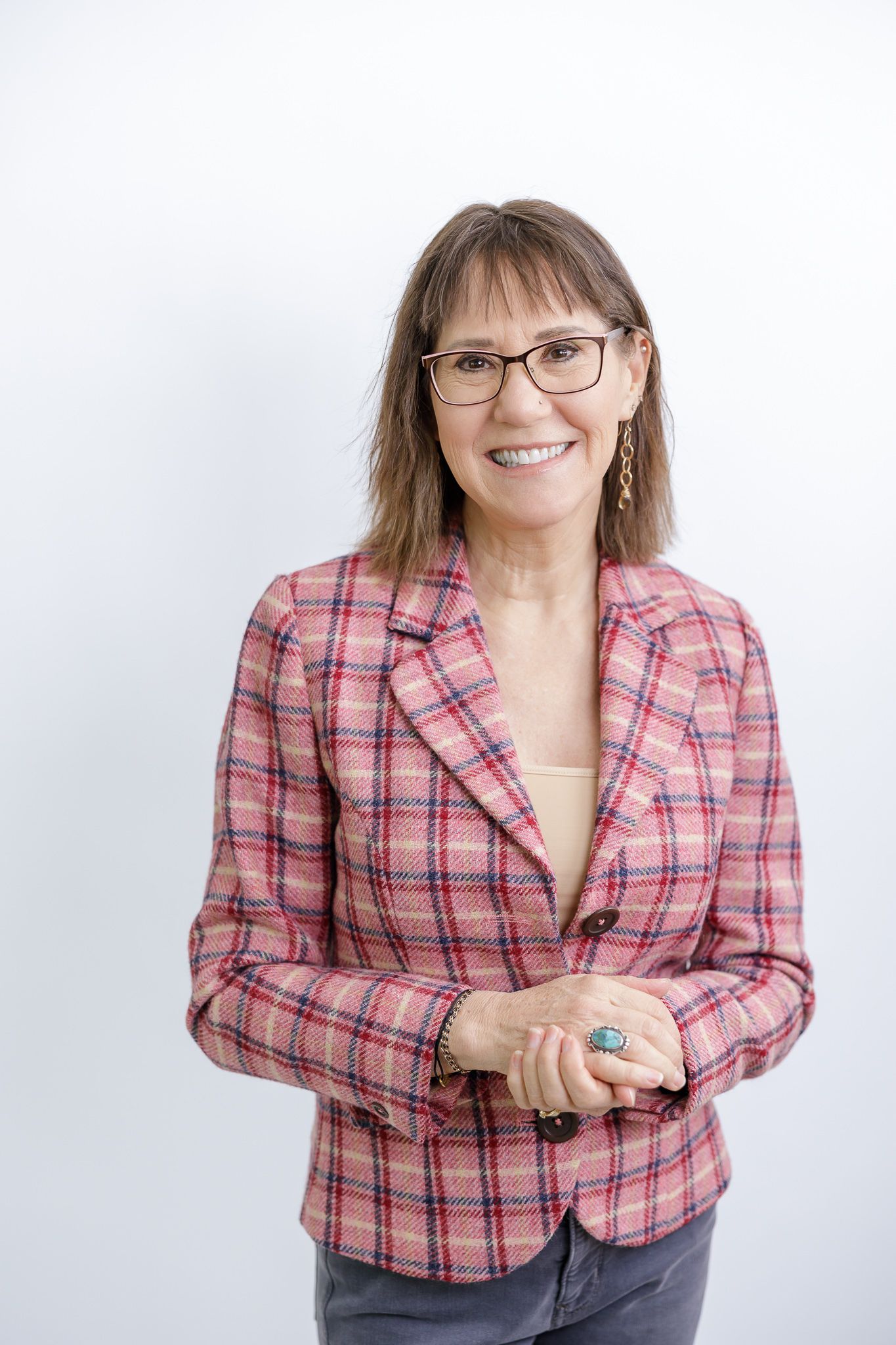woman business owner headshot on white paper smiling at camera in pink striped blazer in Tacoma, wA