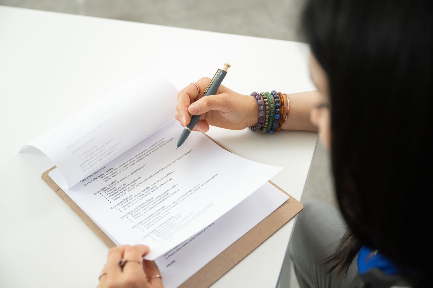 woman brand photographer looking over photoshoot check list for business owner in Seattle, WA holding pen to paper while flipping through