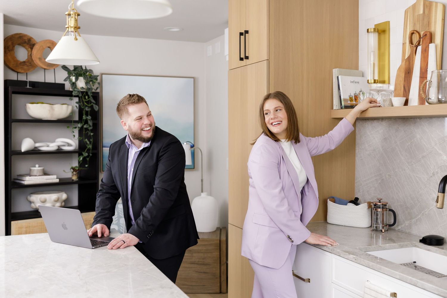 real estate husband wife team branding photo in home kitchen working on laptop and staging items for open house in Bellevue, WA