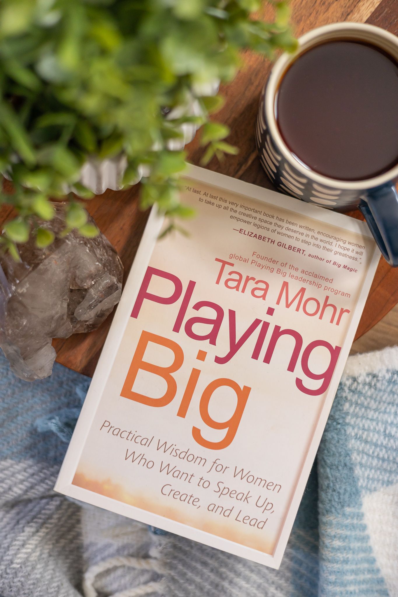 staged flat lay overhead book Playing Big by Tara Mohr on blanket with plant, crystal and cup of tea on table in Seattle, WA