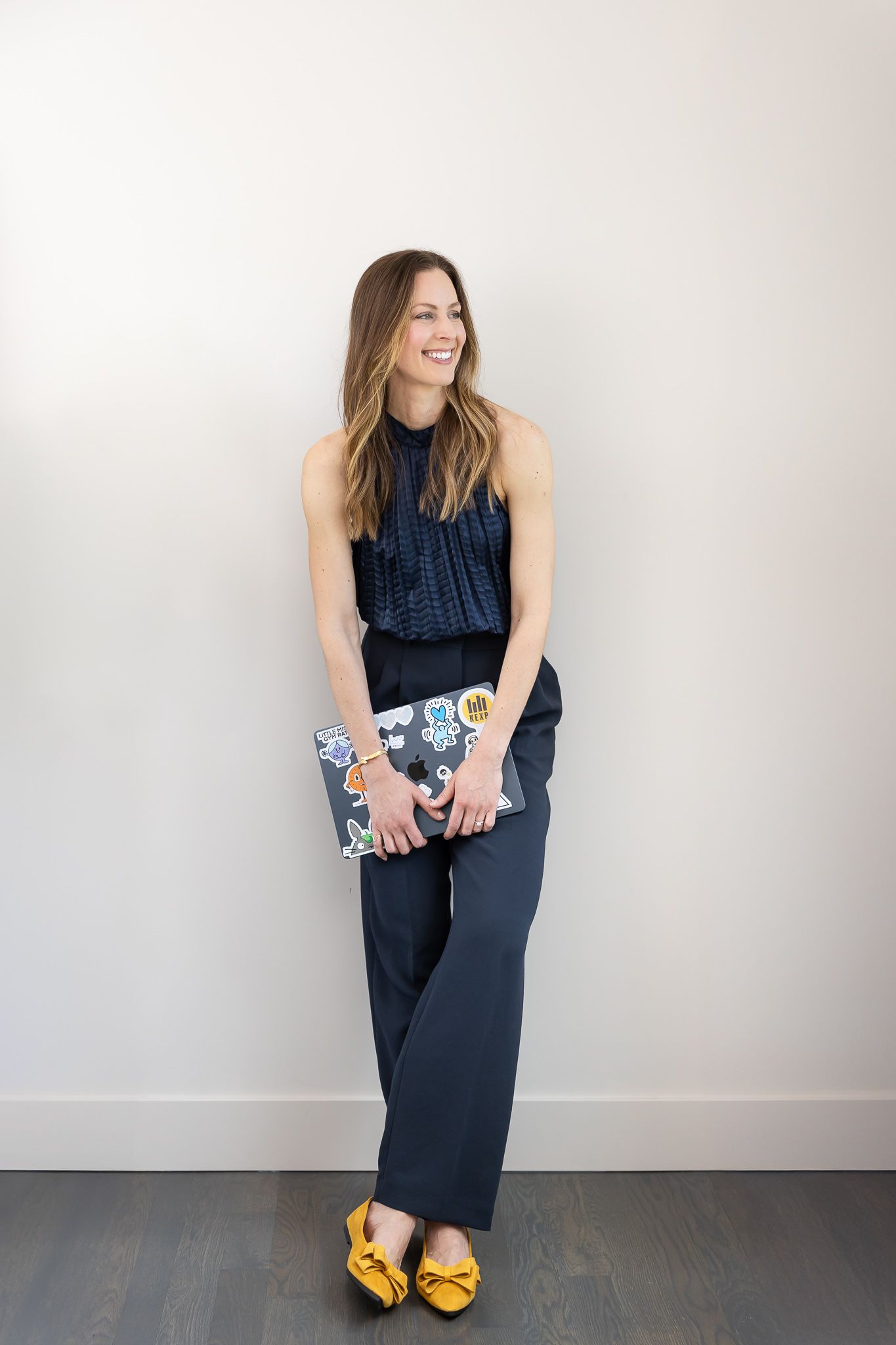 woman business owner SEO strategist in Seattle, WA lifestyle personal branding headshot standing again white wall holding laptop