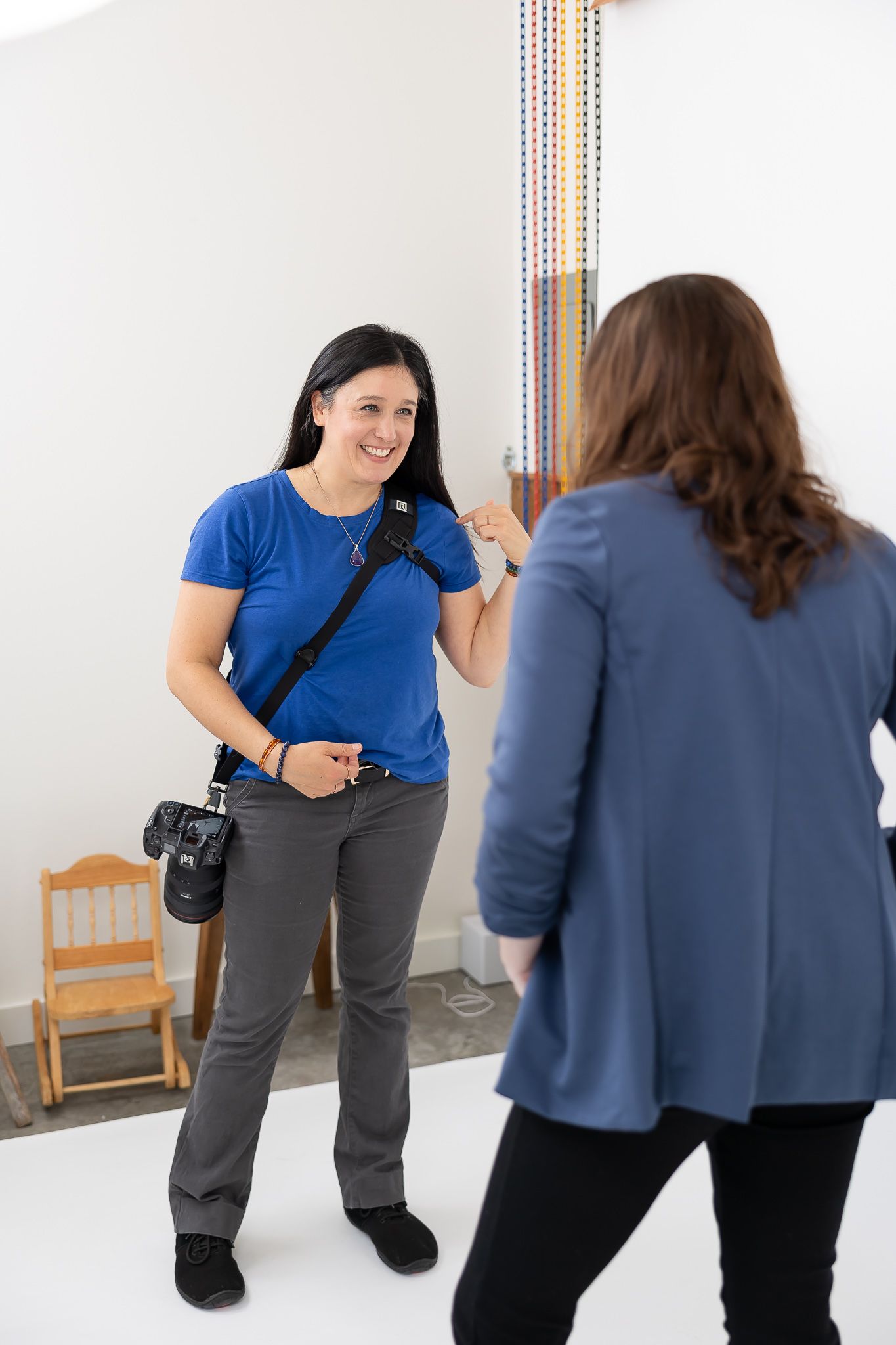 woman brand photographer demonstrating pose to marketing business woman for brand photo in Seattle, WA in studio on white backdrop paper