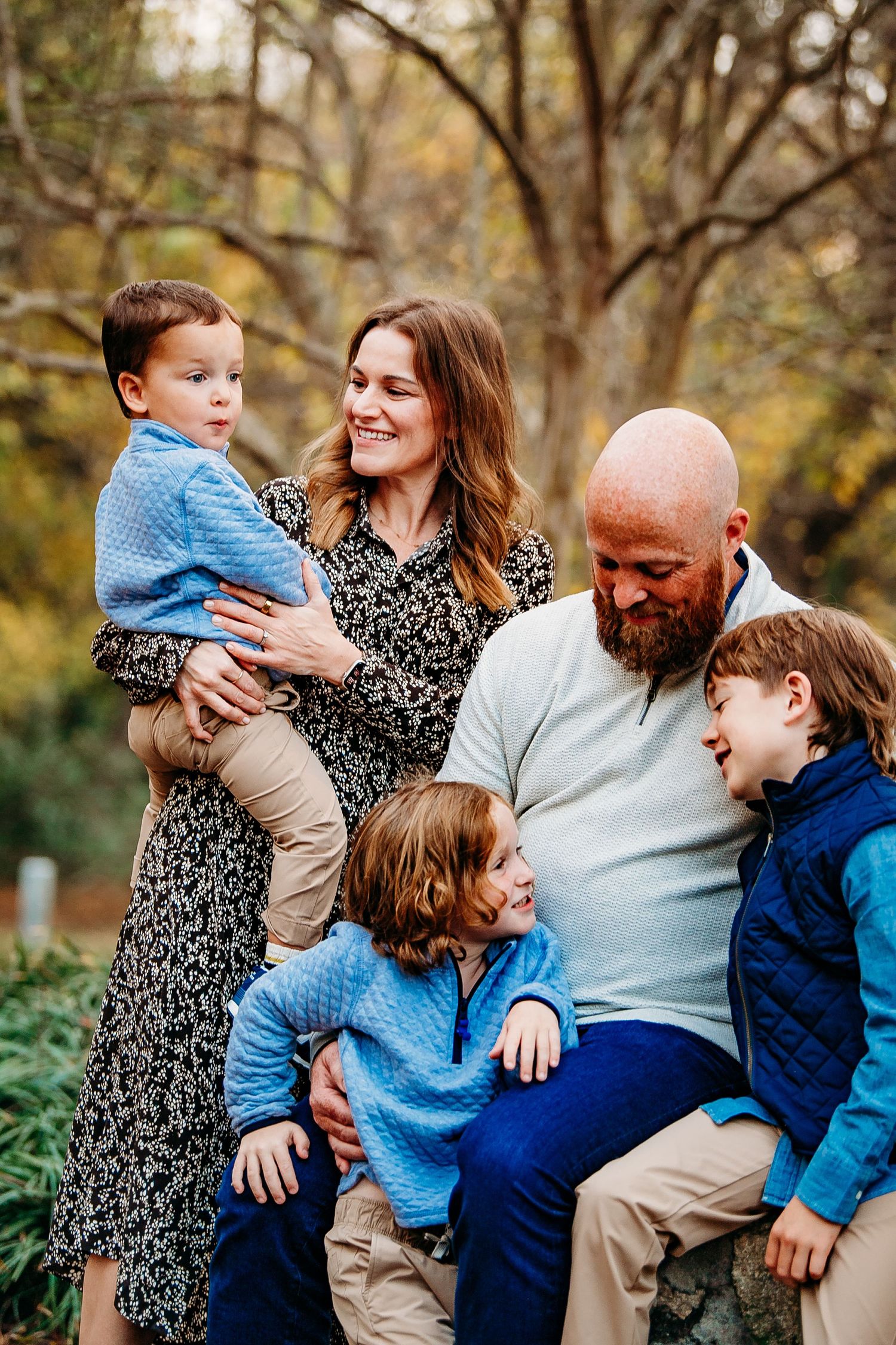 Joyful family of five sharing a candid moment outdoors among colorful fall foliage.
