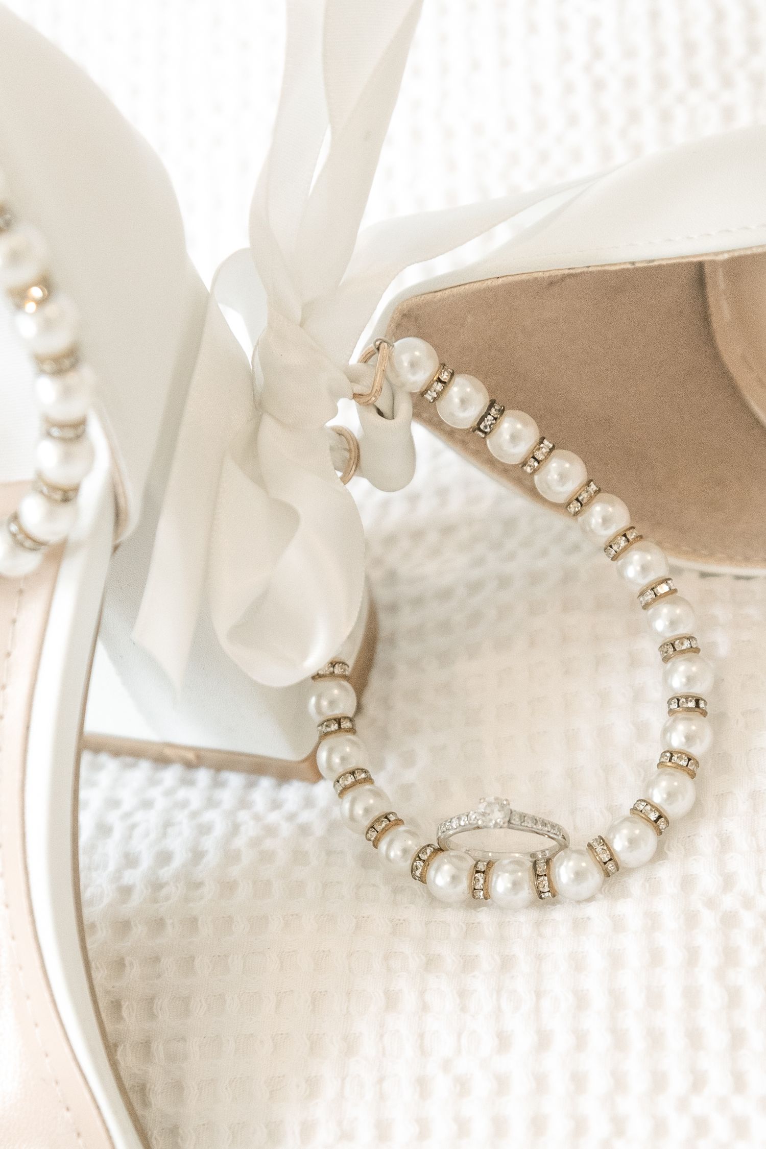 Elegant pearl and gold beaded jewelry pieces laid out on white textured fabric in soft lighting.