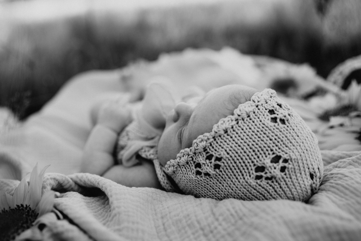 Monochrome close-up of intricate knitted baby clothing with eyelet pattern.