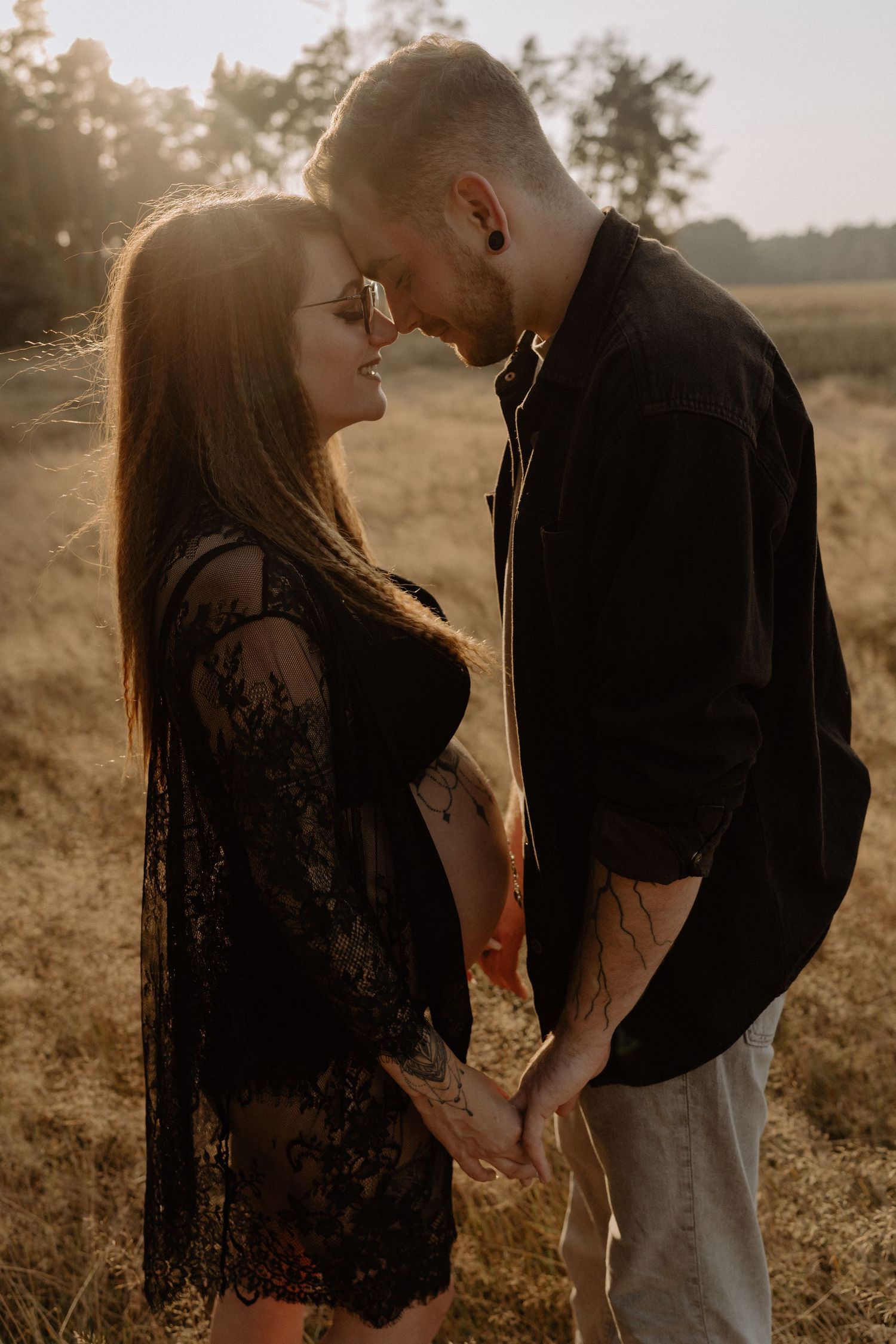 An intimate sunset portrait of a couple sharing a tender moment in a field.
