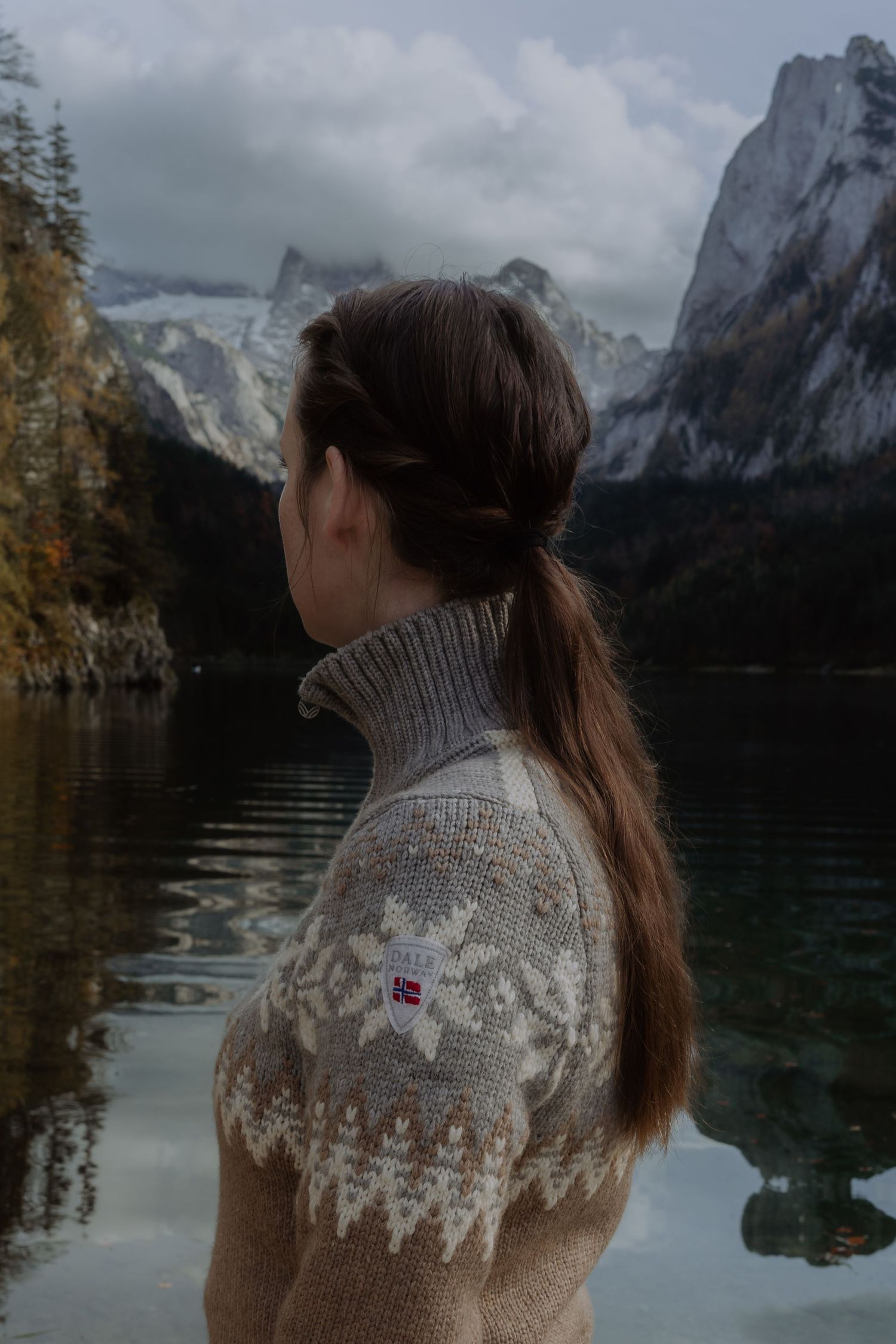 Nordic sweater against mountain landscape with lake reflections in muted tones.