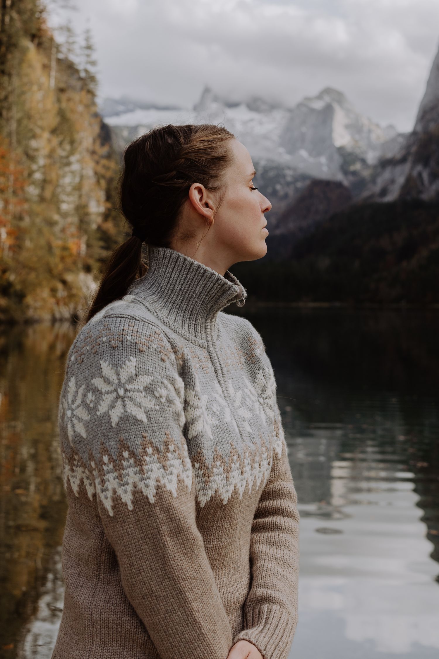 Someone in a cozy knit sweater gazing at mountain lake scenery in autumn.