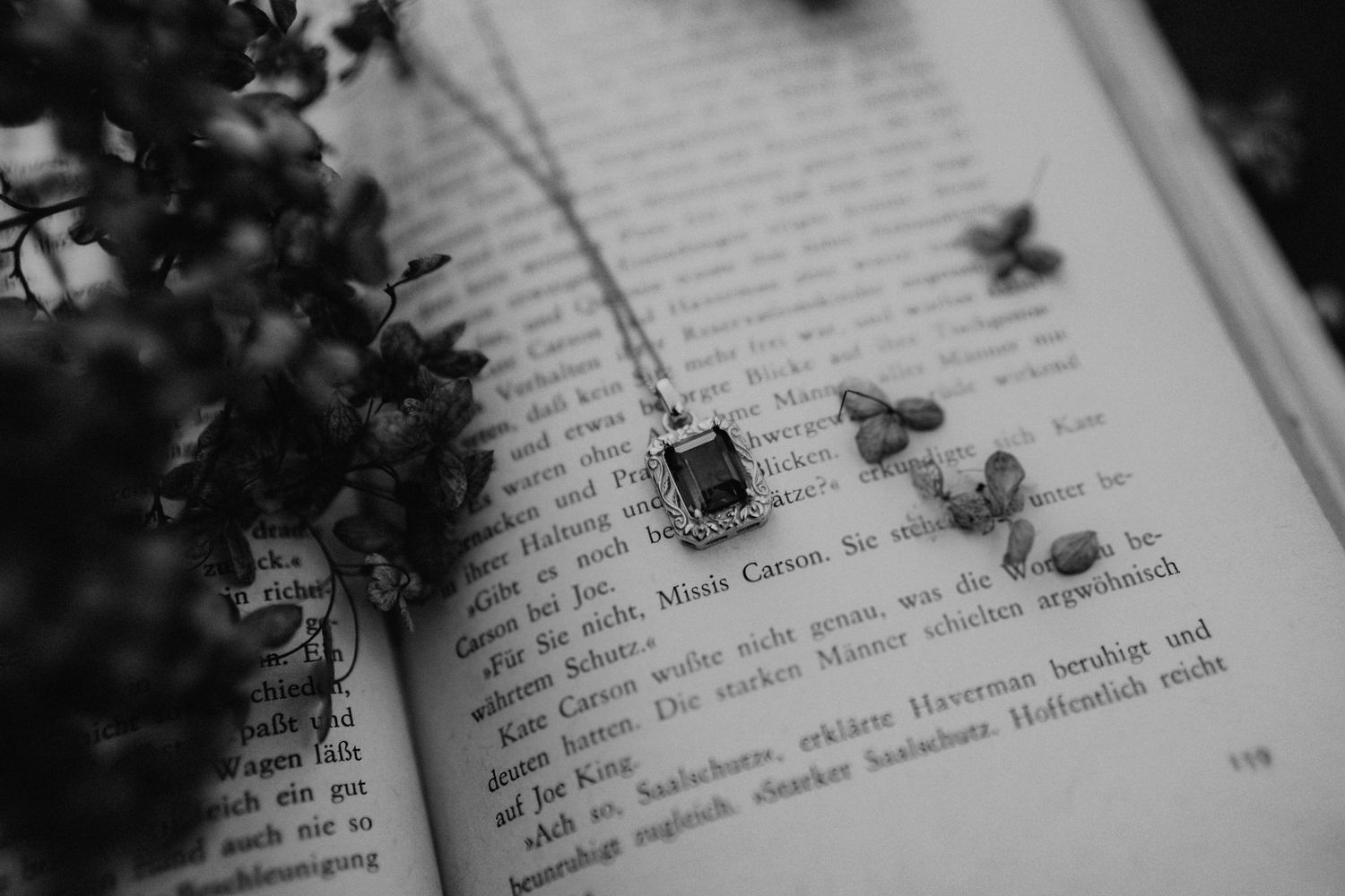 Macro shot of text on book page with delicate flowers in black and white.