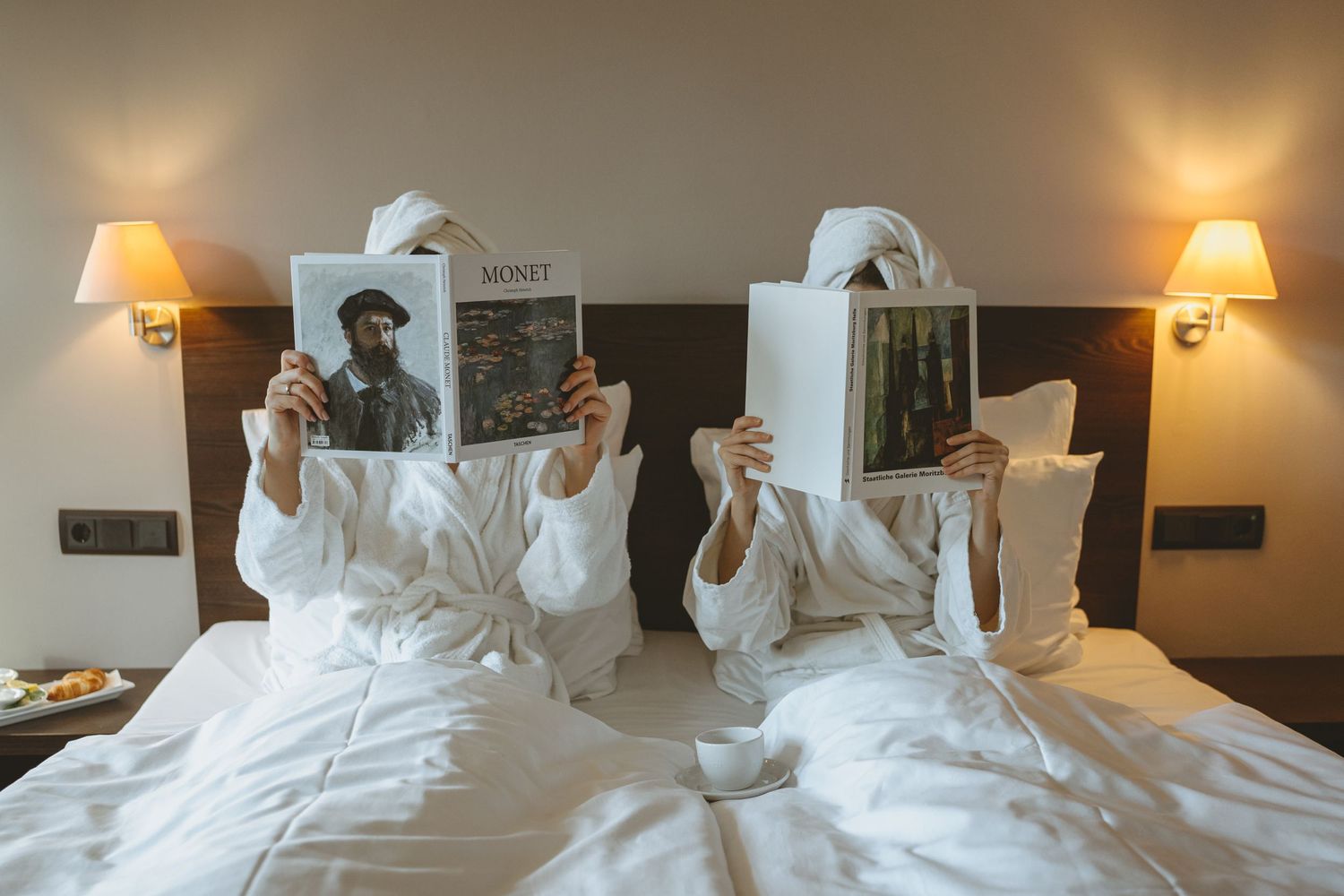 Two people reading books in bed with warm lighting from bedside lamps.