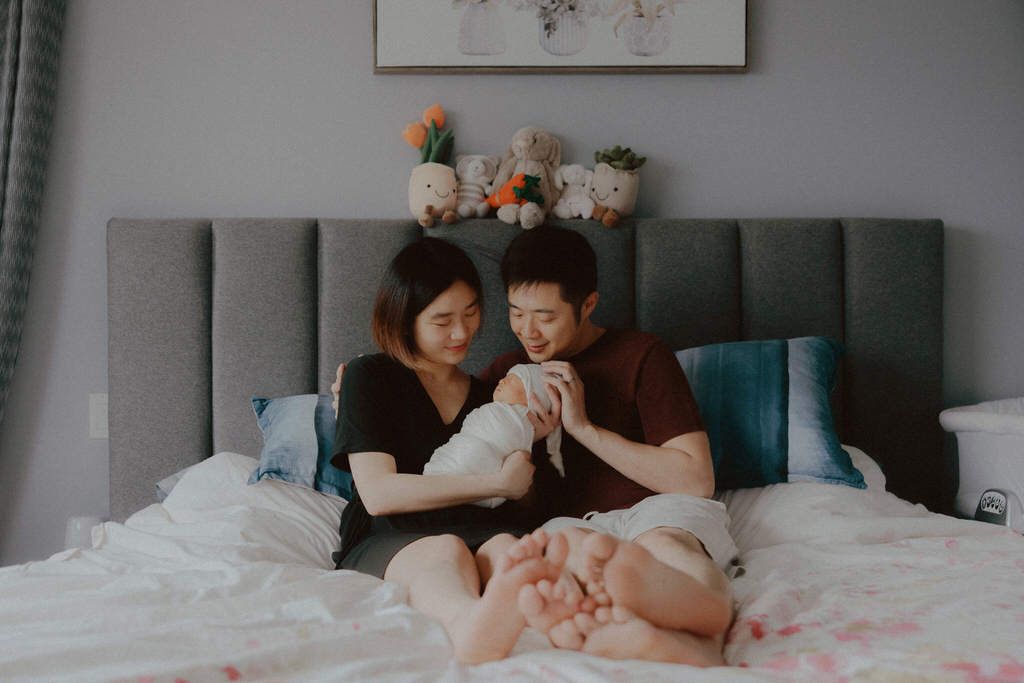 New parents holding their newborn baby in a cozy, natural light setting | Calgary lifestyle photographer capturing heartfelt family moments.