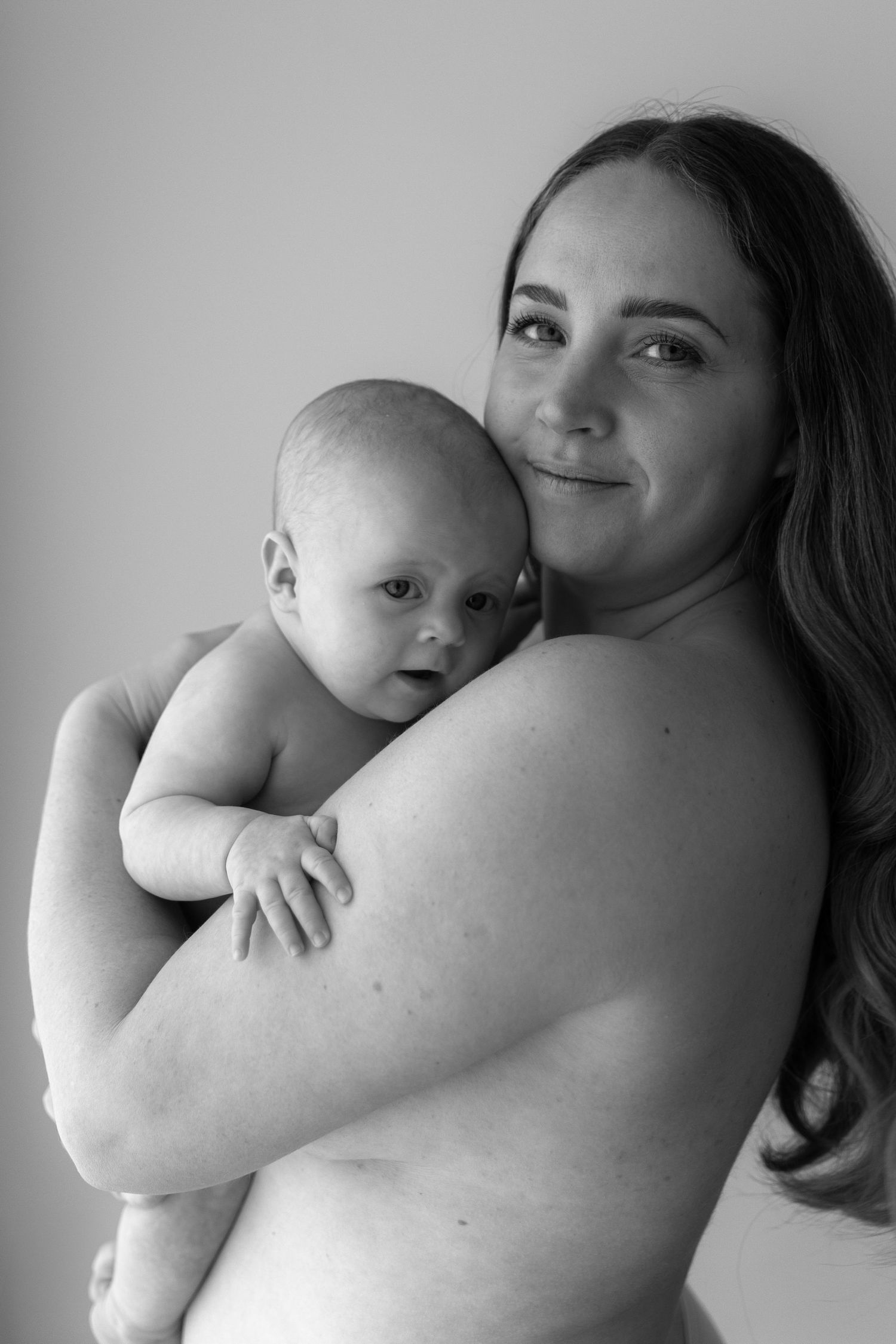 Intimate black and white portrait of parent and baby sharing tender moment.