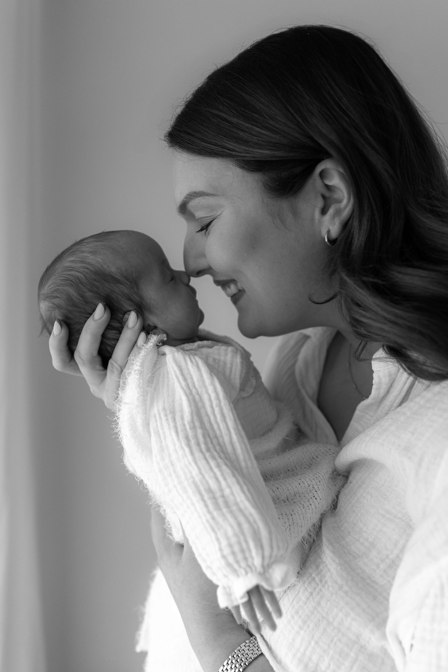 Tender black and white portrait of parent cradling newborn in white sweater.