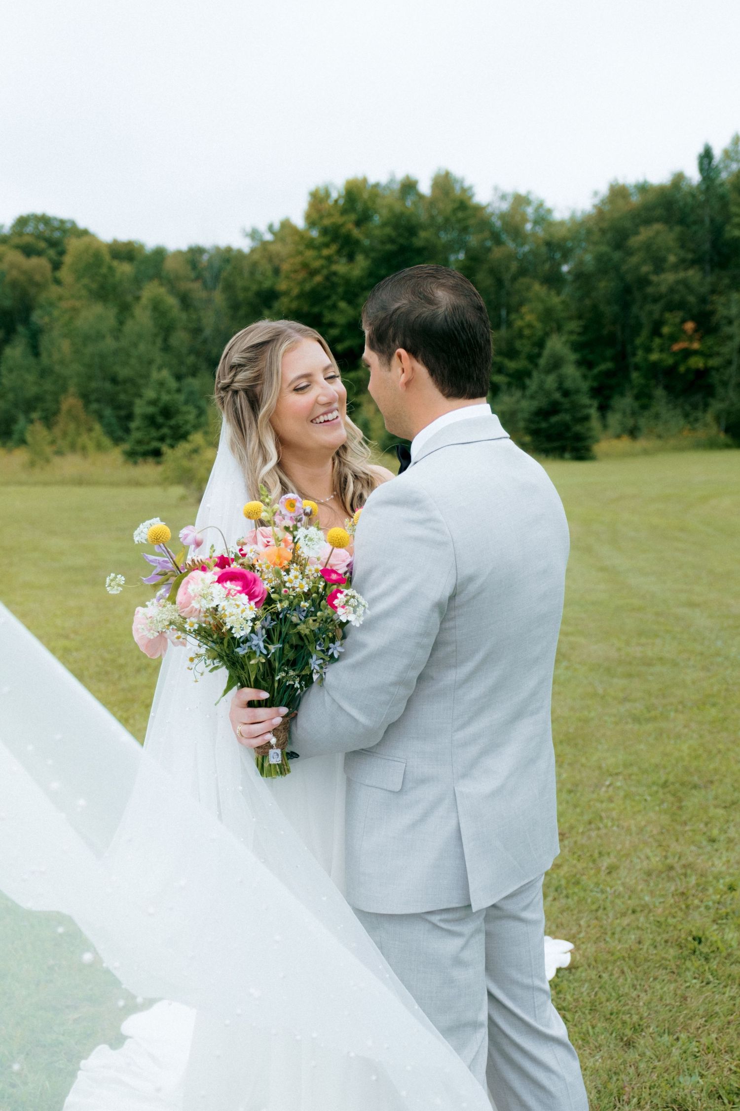 A candid moment between newlyweds outdoors with a colorful bouquet.