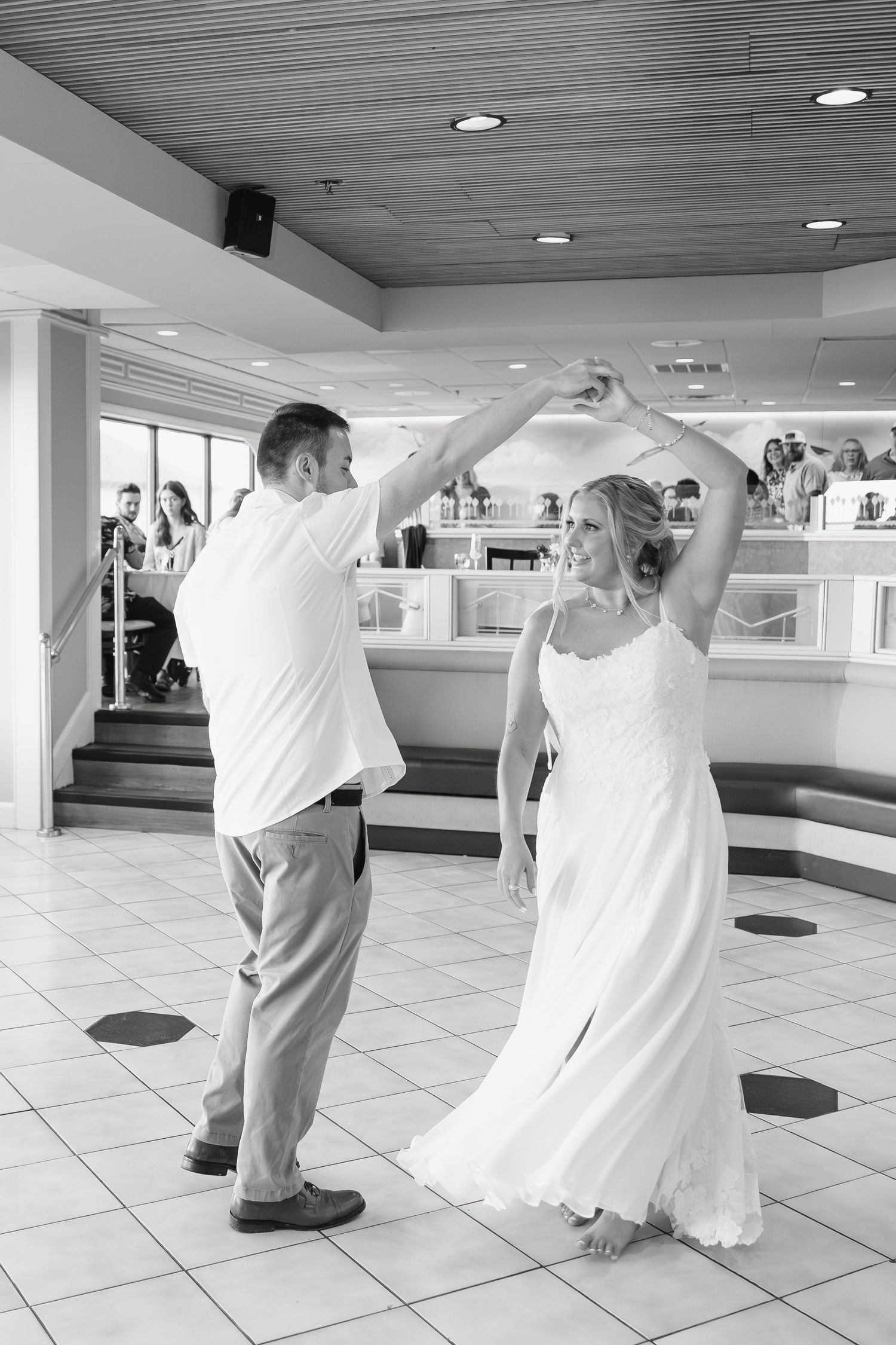 Black and white photo of a bride and groom sharing their first dance at a wedding reception venue.